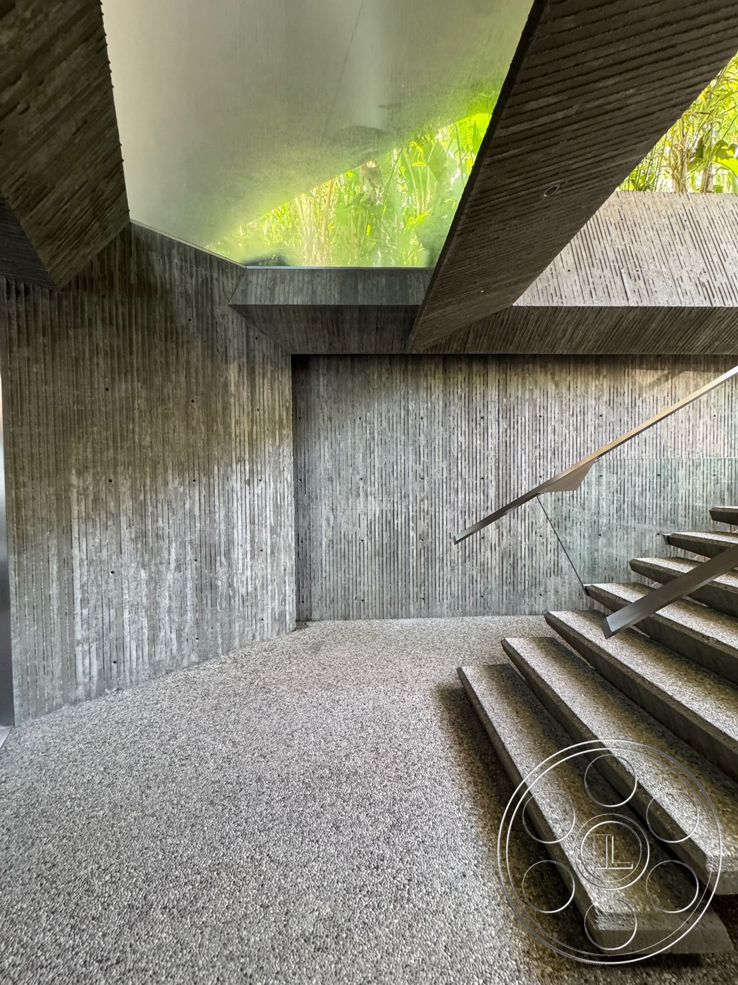 Goldstein House - exposed concrete walls, modern architectural style, gravel flooring, metal stair railing, textured concrete surfaces, floating concrete steps, rough concrete staircase, sloped ceiling with glass skylight