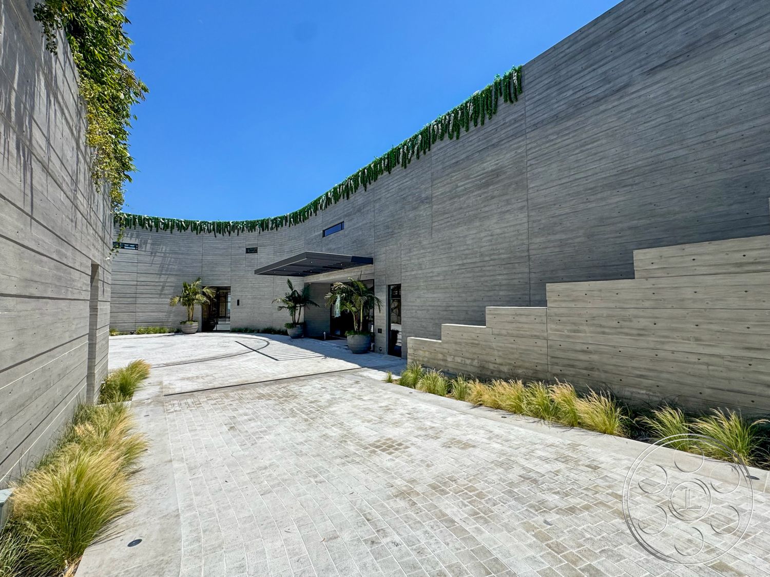 Star Villa - exterior, exposed concrete walls, floor-to-ceiling windows, modern architectural style, curved driveway, landscaped garden beds, staircase with concrete steps, textured concrete paving, greenery on roof edge, entrance with overhang, outdoor planter arrangements