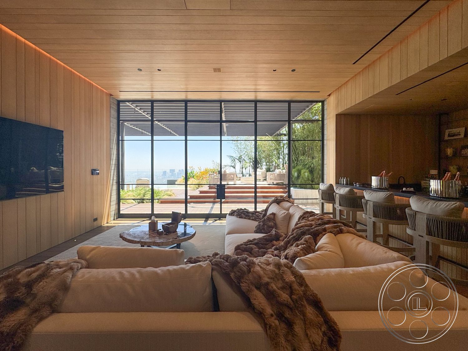 Star Villa - minimalist decor, open floor plan, glass sliding doors, floor-to-ceiling windows, urban skyline view, round wood coffee table, concrete patio flooring, wood beam ceiling, wood paneling walls, soft fabric sectional sofa, bar area with wooden countertop, bamboo plants in view