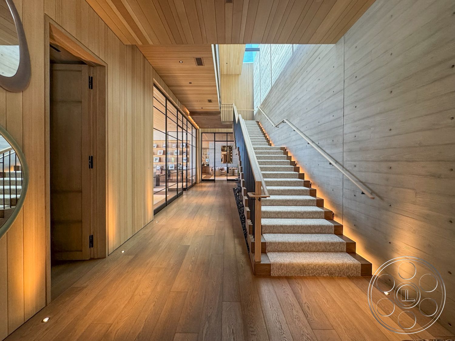 Star Villa - recessed lighting, exposed concrete wall, glass partition walls, modern minimalist design, skylight ceiling, metal stair railings, interior wooden wall paneling, interior hardwood hallway flooring, decorative circular mirror, carpeted staircase with wooden steps