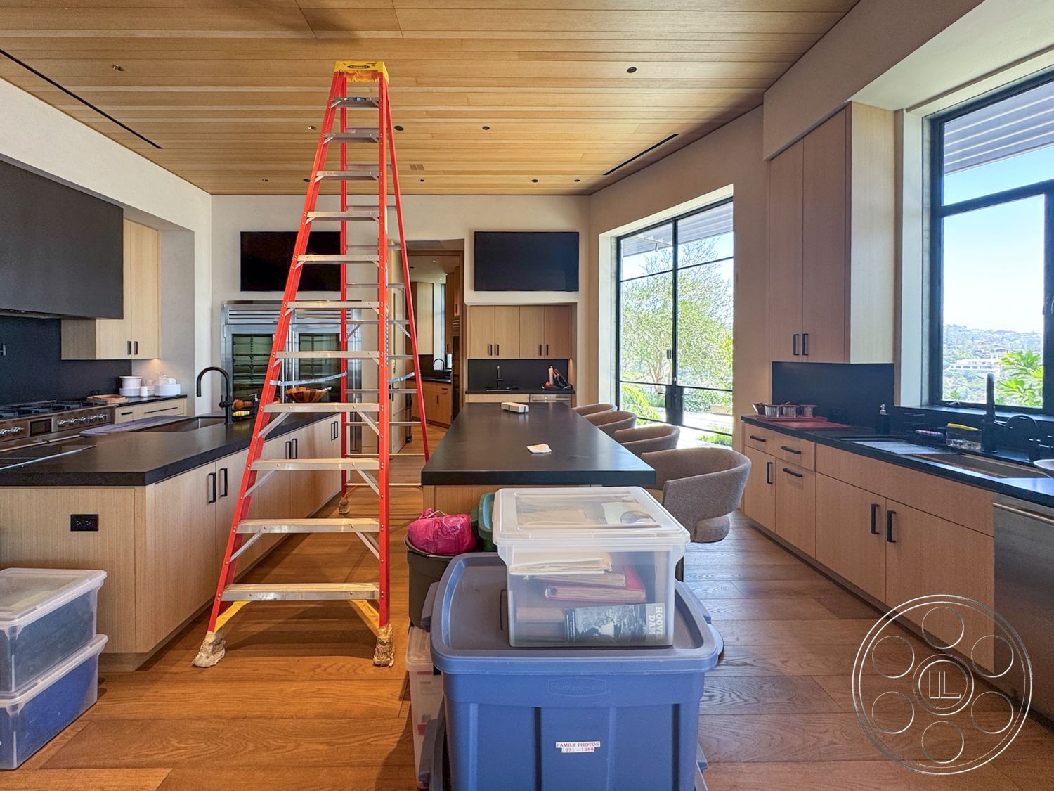 Star Villa - hardwood flooring, stainless steel appliances, light wood cabinetry, floor-to-ceiling windows, open-concept layout, black granite countertops, under-cabinet lighting, view of hillside, modern kitchen design, interior kitchen, coffered ceiling details, natural light ambiance, light wood ceiling panels, minimalist kitchen style, floating kitchen island, contemporary stools