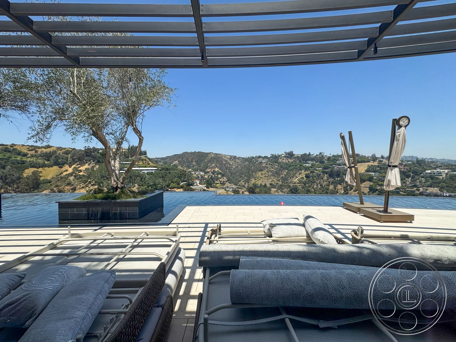 Star Villa - exterior, mountain backdrop, infinity pool, sunshade umbrellas, stone pool deck, concrete patio flooring, landscaped hillside view, metal pergola structure, outdoor loungers with cushions, decorative planters with trees