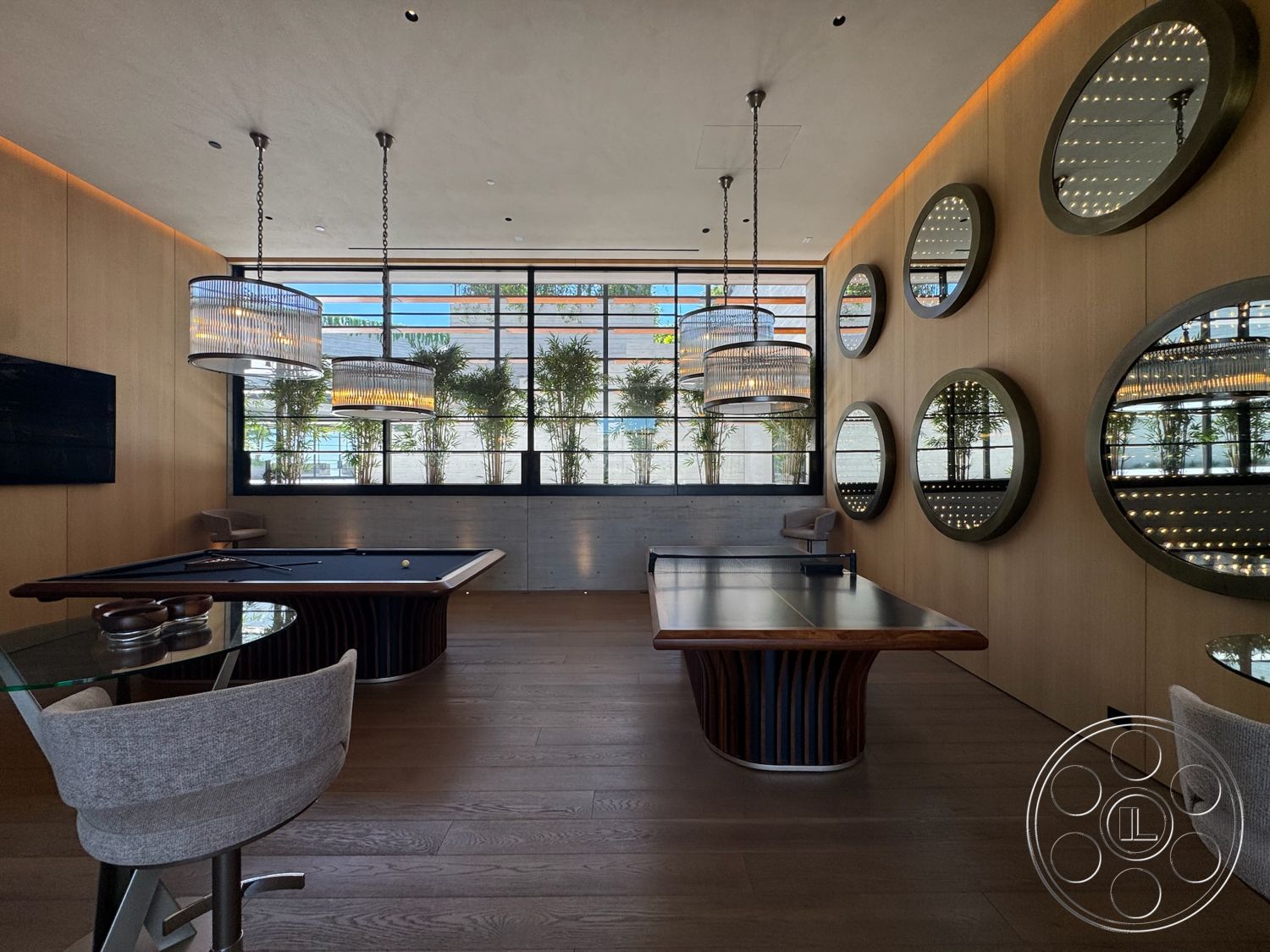 Star Villa - wood flooring, modern lighting fixtures, dark wood table, natural light from large windows, pool table, circular mirrors, wood paneling walls, pendant chandeliers, glass-topped table, upholstered bar stools, bamboo planters