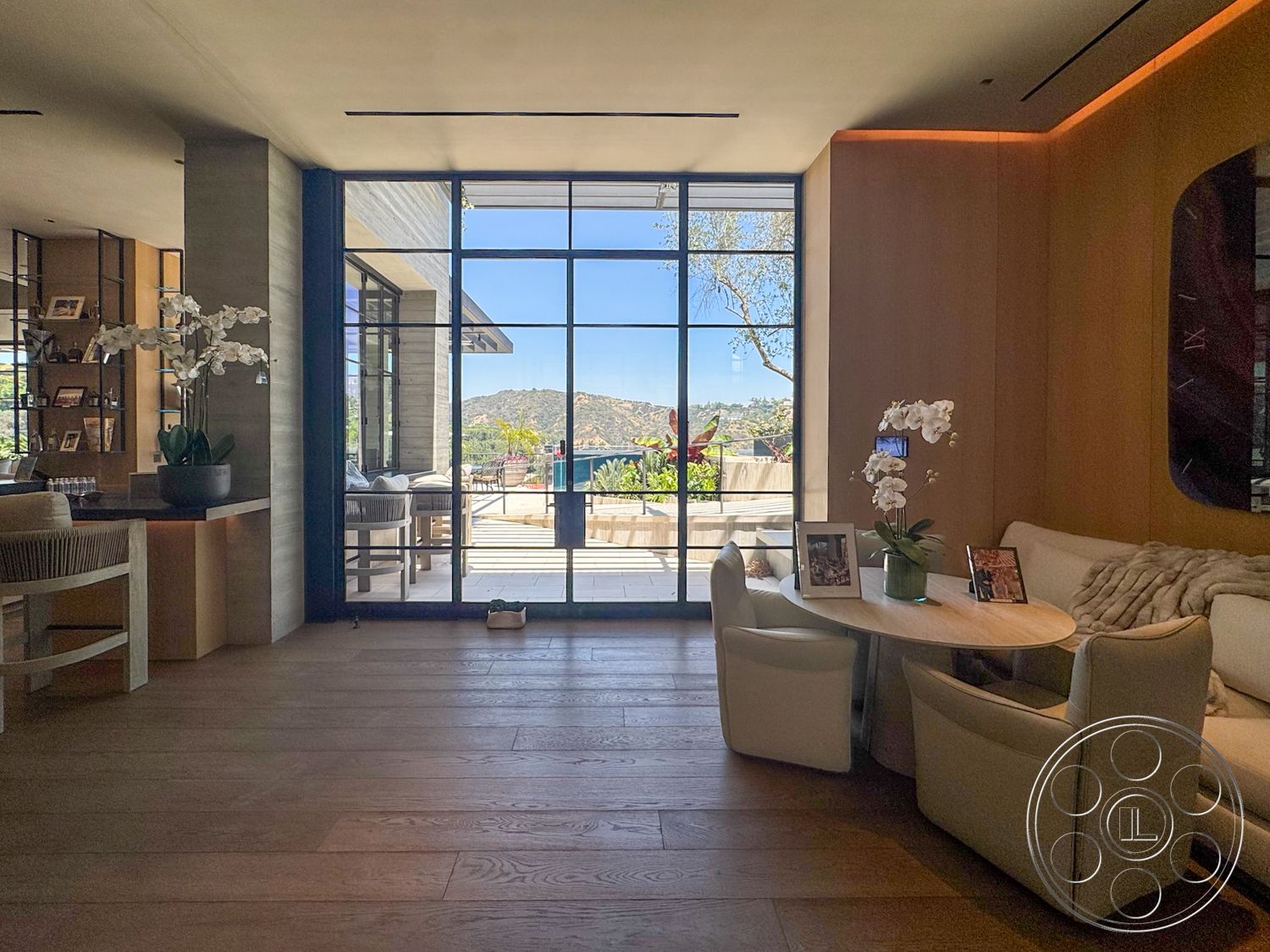 Star Villa - floor-to-ceiling windows, round dining table, built-in bookshelf, modern minimalist decor, light wood accent walls, open floor plan design, natural light filled space, wood plank flooring, panoramic mountain view, large panoramic window wall, curved white upholstered chairs, decorative potted orchids