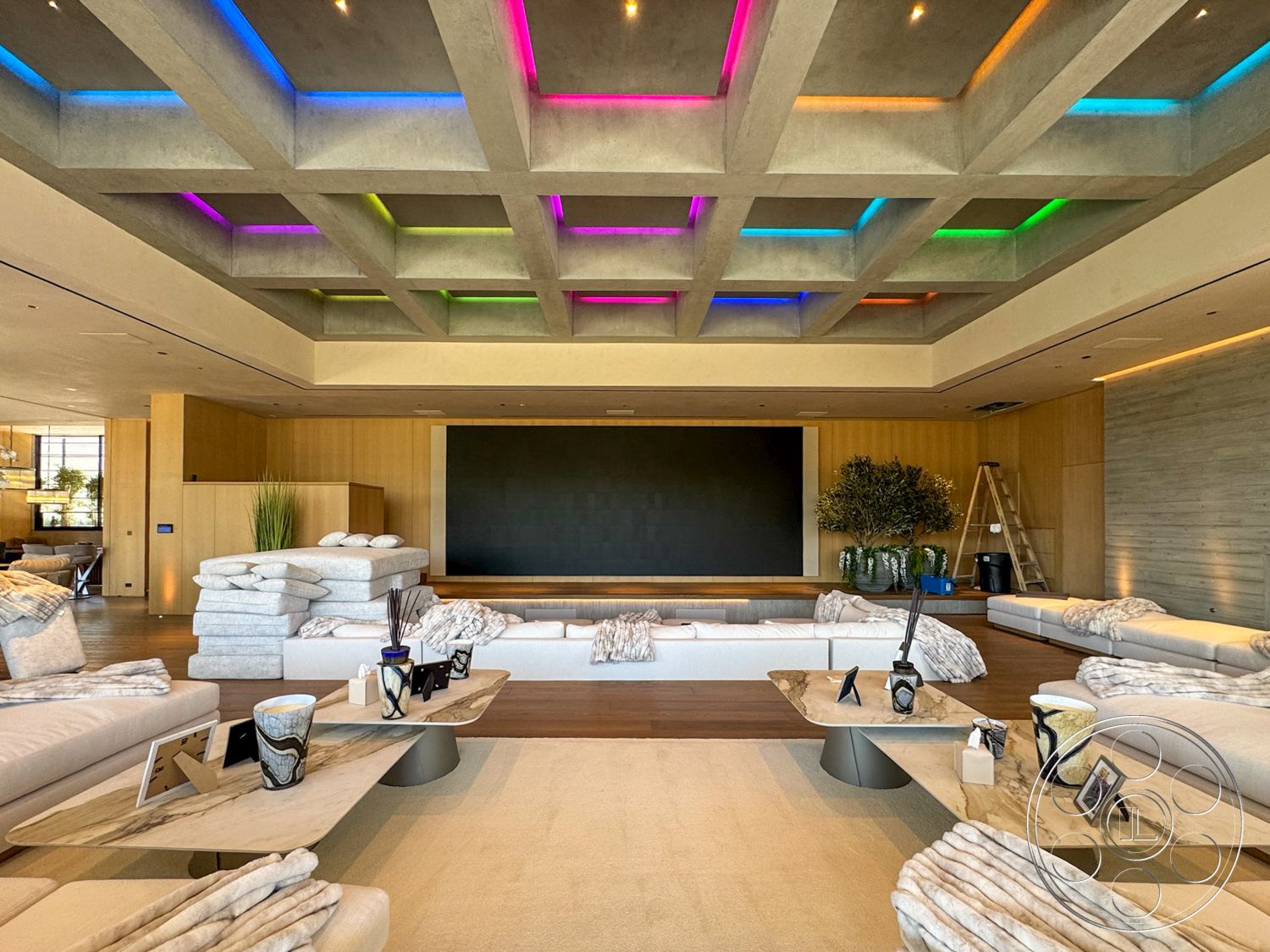 Star Villa - light hardwood flooring, floor-to-ceiling windows, concrete ceiling, textured throw blankets, modern minimalist decor, wood paneling on walls, marble tabletop, coffered ceiling with colored LED lighting, rectangular coffee tables, plush sectional sofas, large wall-mounted TV area, natural greenery in vases
