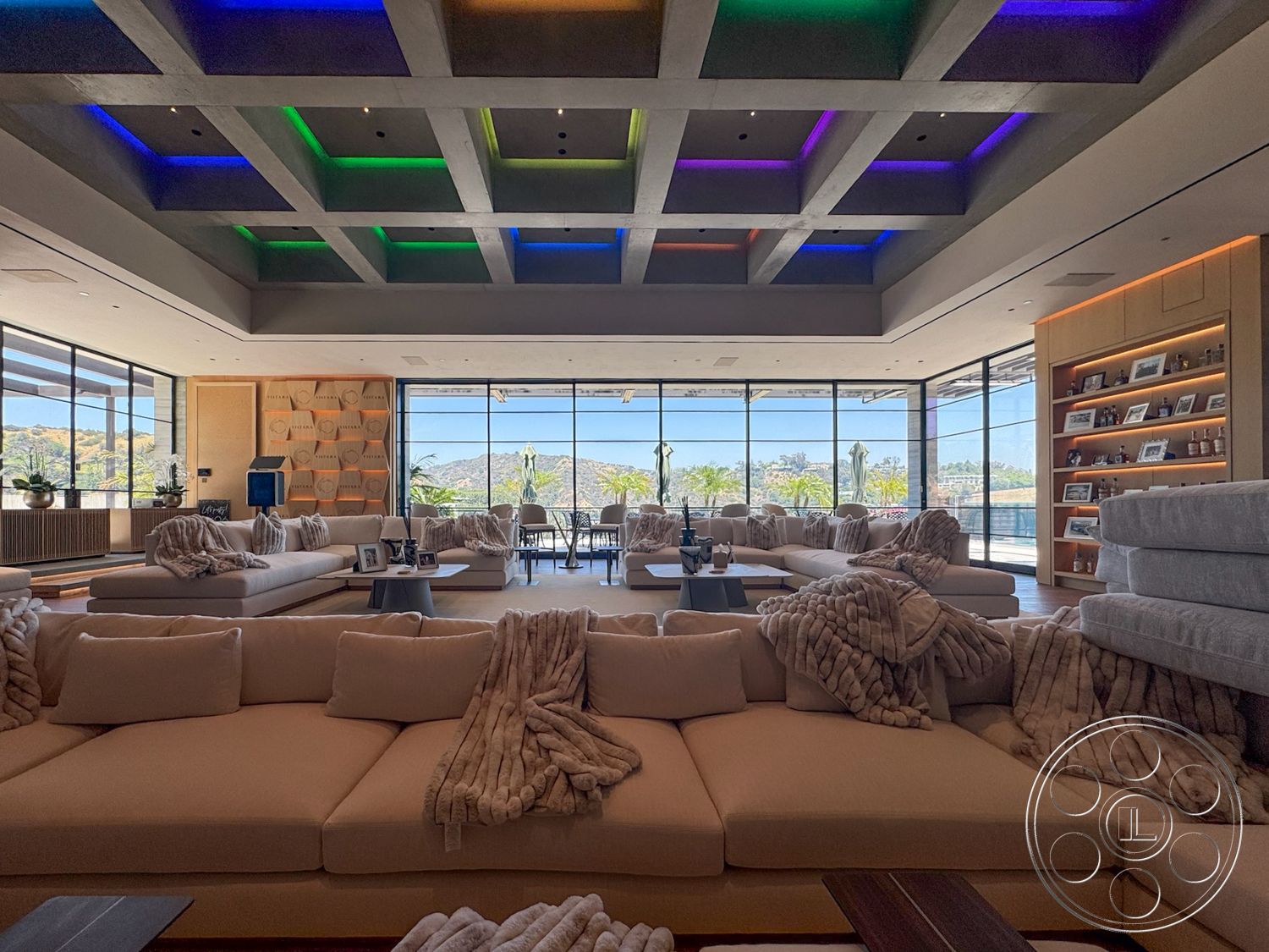 Star Villa - open floor plan, plush sectional sofa, floor-to-ceiling windows, textured wall panels, mountain view, hardwood floor, modern lounge area, built-in wooden shelving, LED accent lighting, concrete coffered ceiling, coffee table with decorative elements