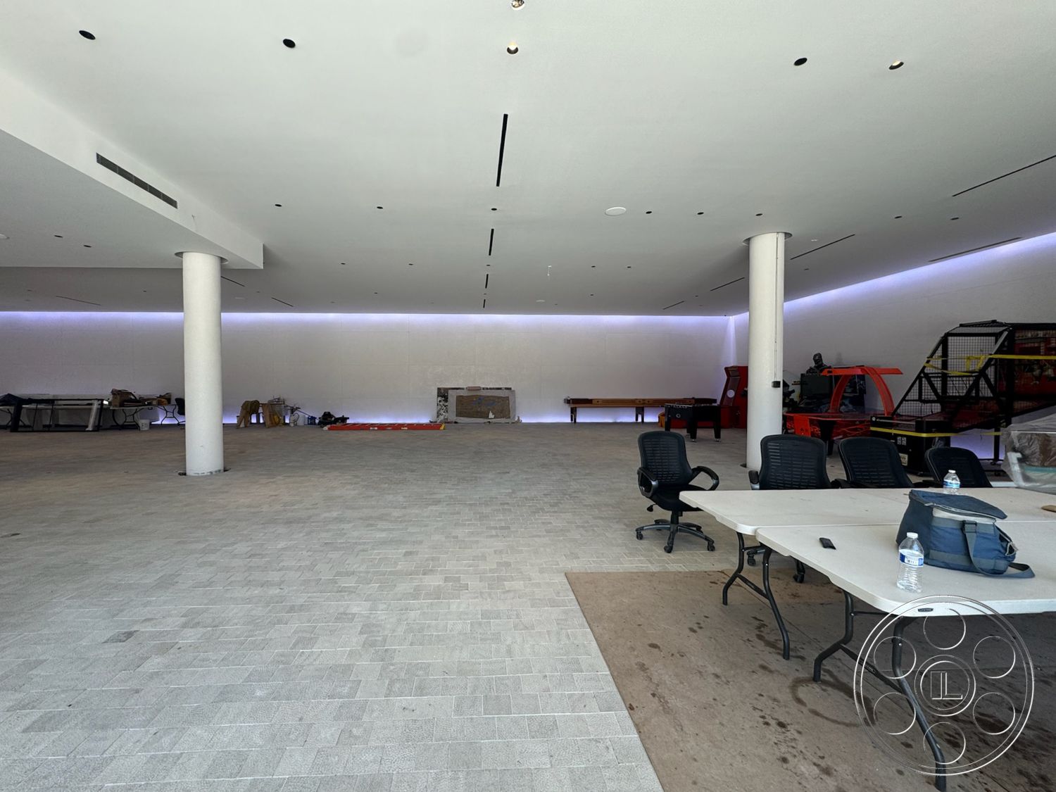 Star Villa - textured plaster walls, LED ambient lighting, recessed ceiling lights, modern minimalist design, open layout space, light-colored concrete flooring, round concrete columns, unfinished construction elements, temporary furniture setup