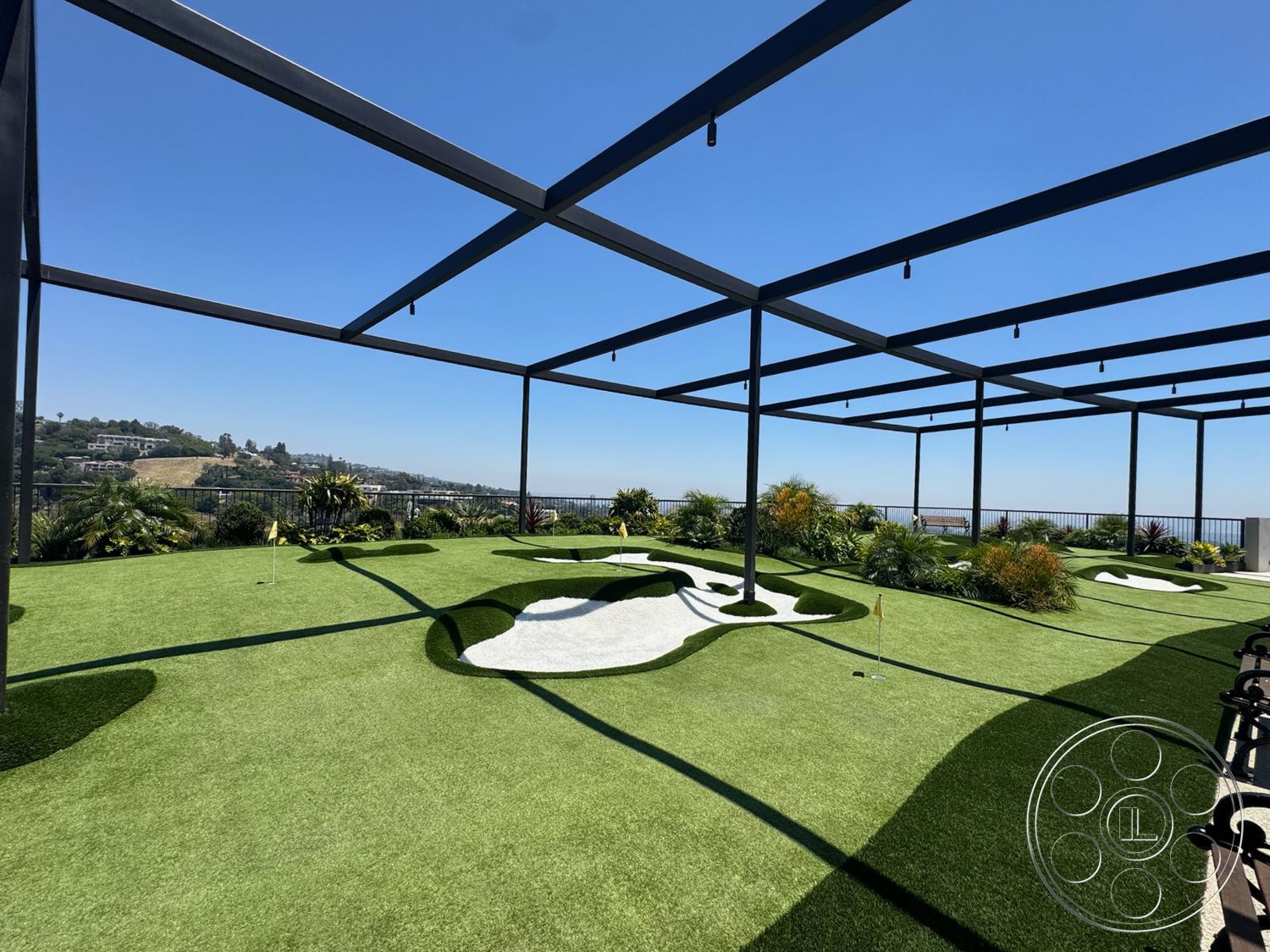Star Villa - exterior, city skyline view, outdoor recreational space, golf putting green, landscaped garden beds, tropical plant landscaping, metal pergola structure, synthetic grass surface, white gravel areas, curved lawn shapes