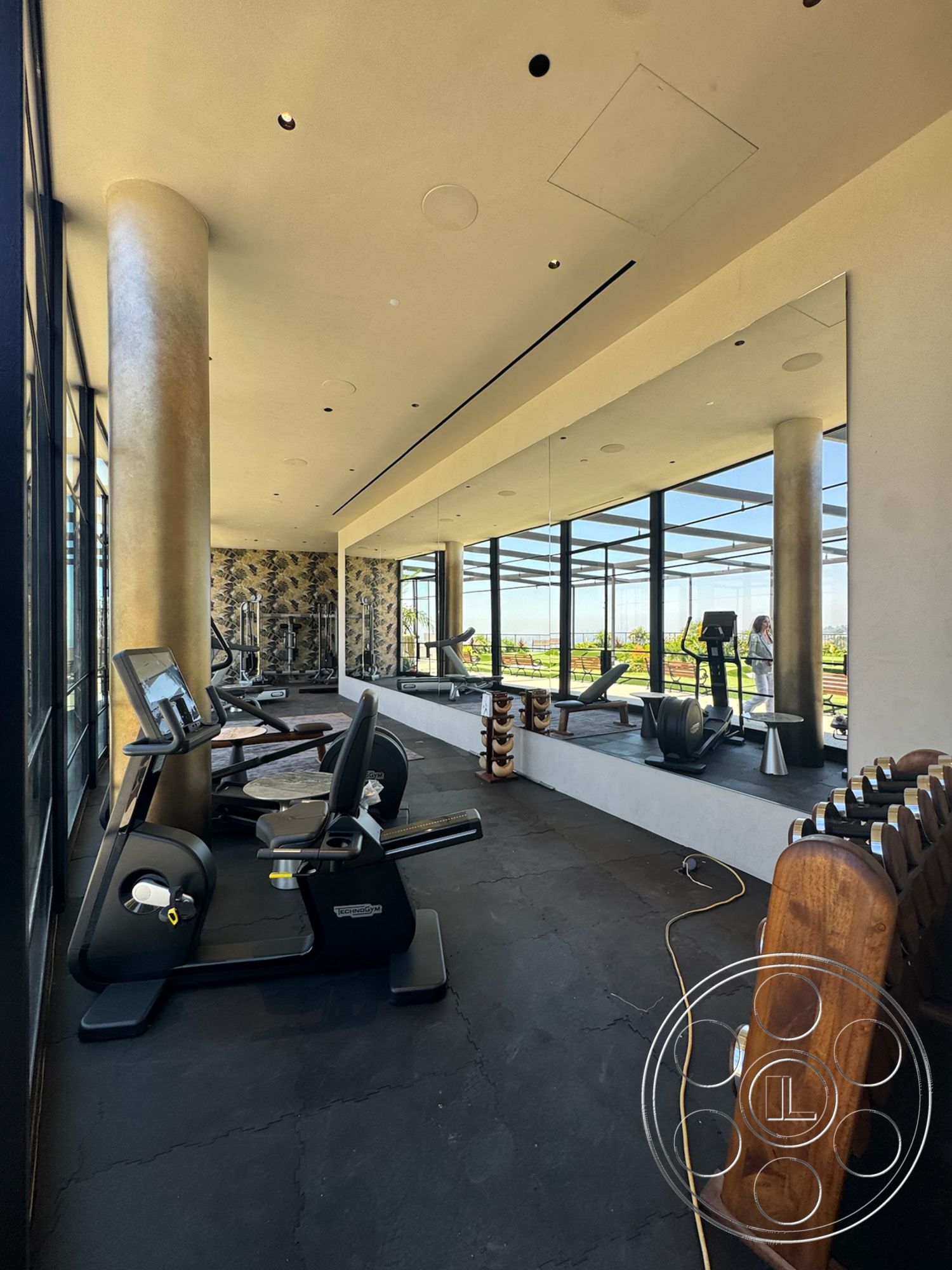 Star Villa - floor-to-ceiling windows, high ceilings with recessed lighting, modern fitness equipment, rubber gym flooring, large wall mirror, golden polished column, decorative wallpaper accent wall, open gym layout, wooden weight rack