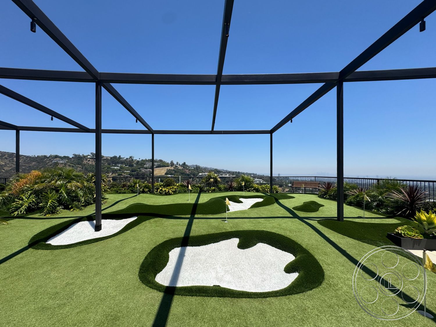 Star Villa - exterior, open-air structure, steel frame structure, flat roof design, landscaped garden with tropical plants, mountain view backdrop, synthetic grass putting green, white sand traps, overhead trellis beams, golf course layout