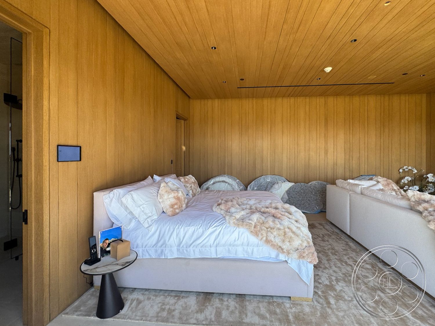Star Villa - decorative vases, white bedding, king-sized bed, modern sofa, minimalist bedside table, wood paneling walls, horizontal wood slat ceiling, plush beige area rug, neutral textured throw blanket, dark wood bedroom door