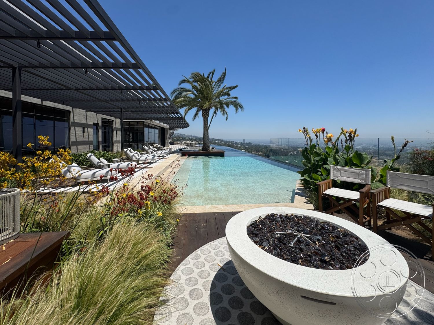 Star Villa - exterior, landscaped garden, modern outdoor furniture, tropical plants, city skyline view, sun loungers, infinity pool, desert setting, metal pergola, stone pool deck, wood deck flooring, concrete pool border, glass balcony railings, fire pit with decorative stones