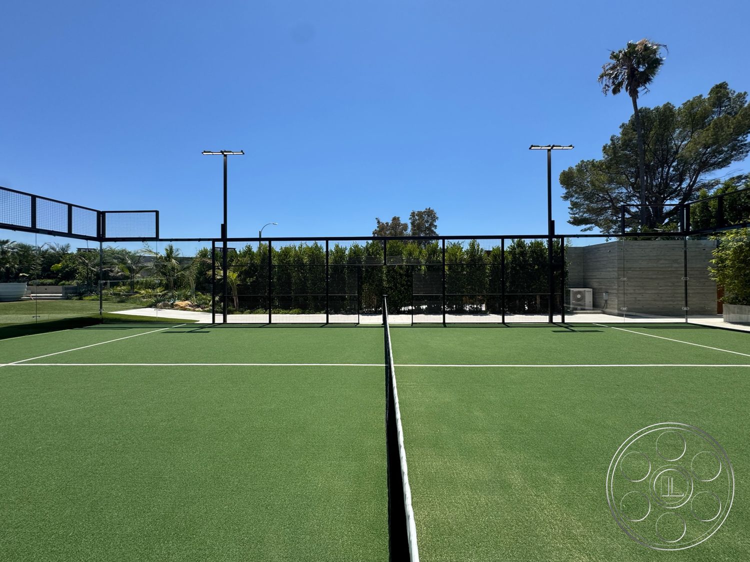 Star Villa - clear blue sky, outdoor sports area, exterior landscaping with palm trees, black metal fencing, artificial turf tennis court, concrete wall surroundings