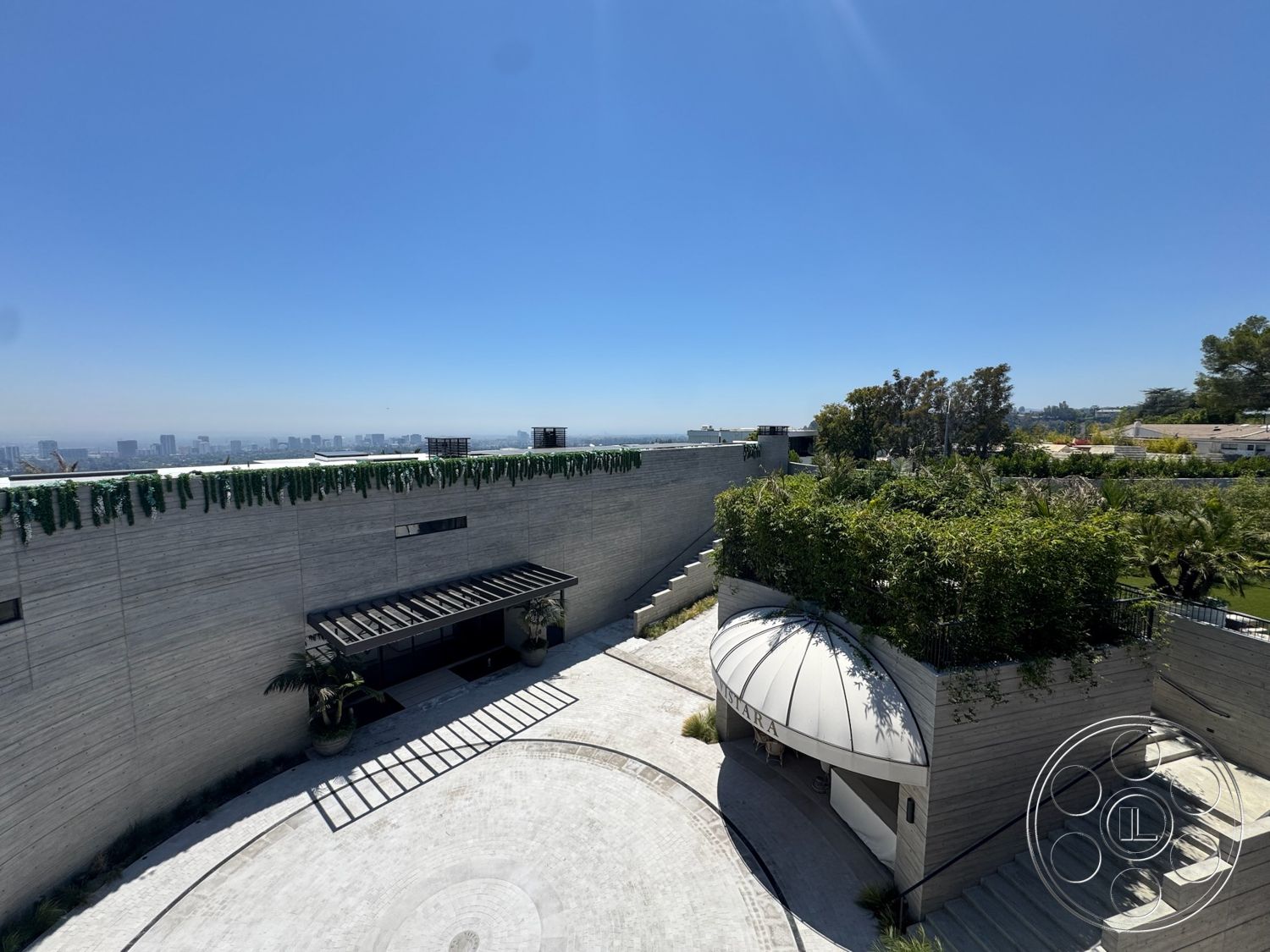 Star Villa - exterior, outdoor living space, curved driveway, terraced landscaping, step pathway, flat roof design, minimalist architectural style, concrete wall facade, landscaped garden with greenery, circular paver stone flooring, metal roof awning, wooden entrance doors, large panoramic city skyline view