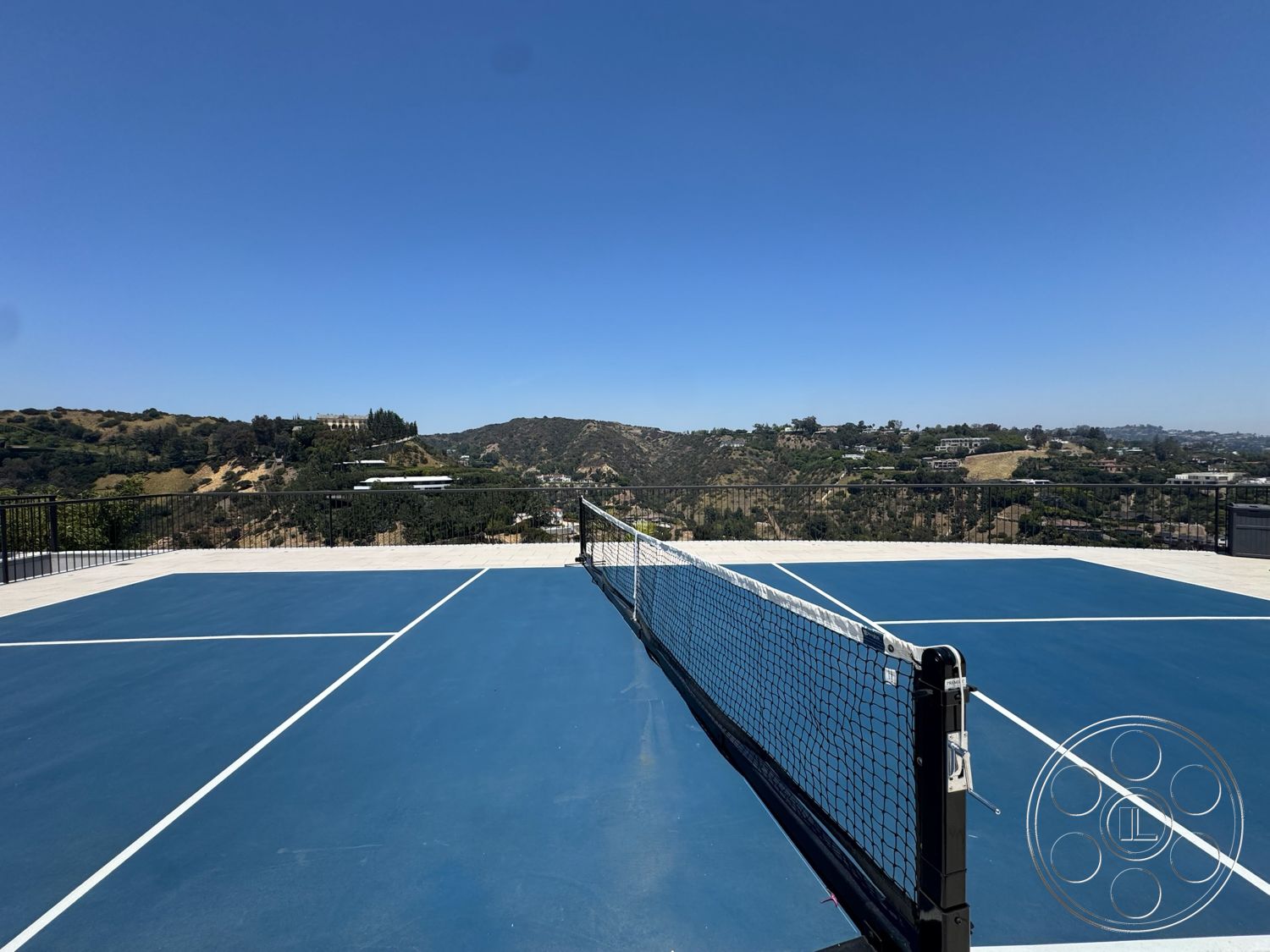 Star Villa - exterior, clear blue sky, hillside location, outdoor sports area, mountain view backdrop, concrete tennis court base, blue tennis court surface, metal tennis net, horizontal metal railing
