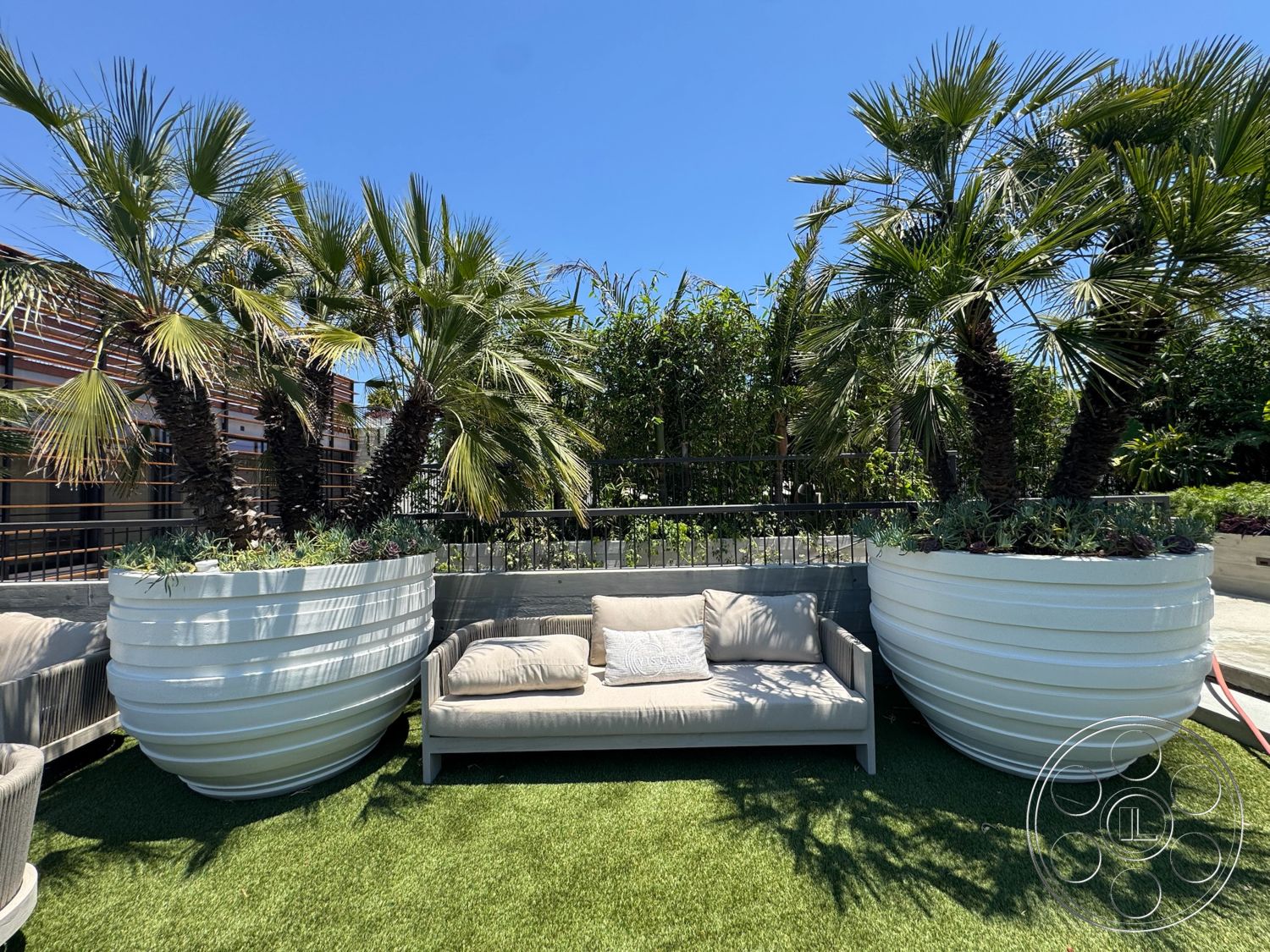 Star Villa - exterior, metal railing, greenery backdrop, contemporary outdoor design, modern outdoor seating, sunny rooftop terrace, artificial grass flooring, curved white planter boxes, palm trees in planters, slatted wood screening