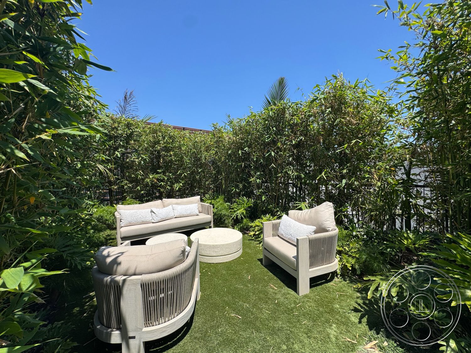 Star Villa - exterior, lush greenery, outdoor seating area, contemporary outdoor furniture, circular coffee table, textured pillows, sunny outdoor setting, artificial grass lawn, bamboo privacy wall
