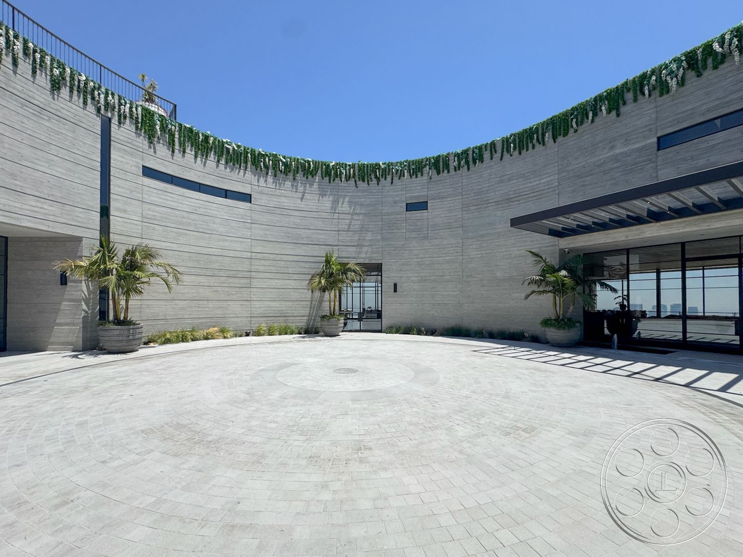 Star Villa - exterior, urban setting, floor-to-ceiling windows, modern architectural style, minimalist facade, curved concrete walls, concrete circular driveway, landscaped garden with palm trees, open entryway design, horizontal wood slat overhang, concrete flooring with circular pattern, greenery wall treatment