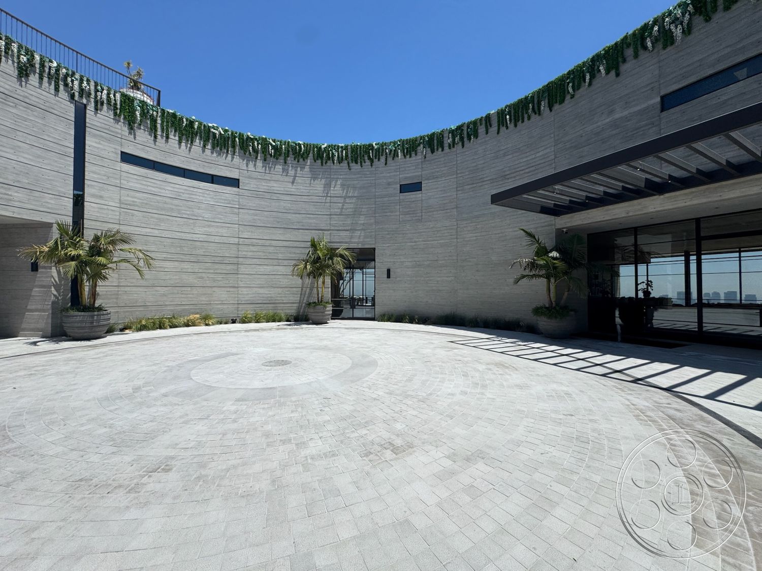 Star Villa - exterior, floor-to-ceiling windows, circular driveway, modern architectural style, landscape greenery, raised garden beds, reinforced concrete walls, porcelain tile flooring, outdoor entrance area, palm trees in planters, overhead trellis structure