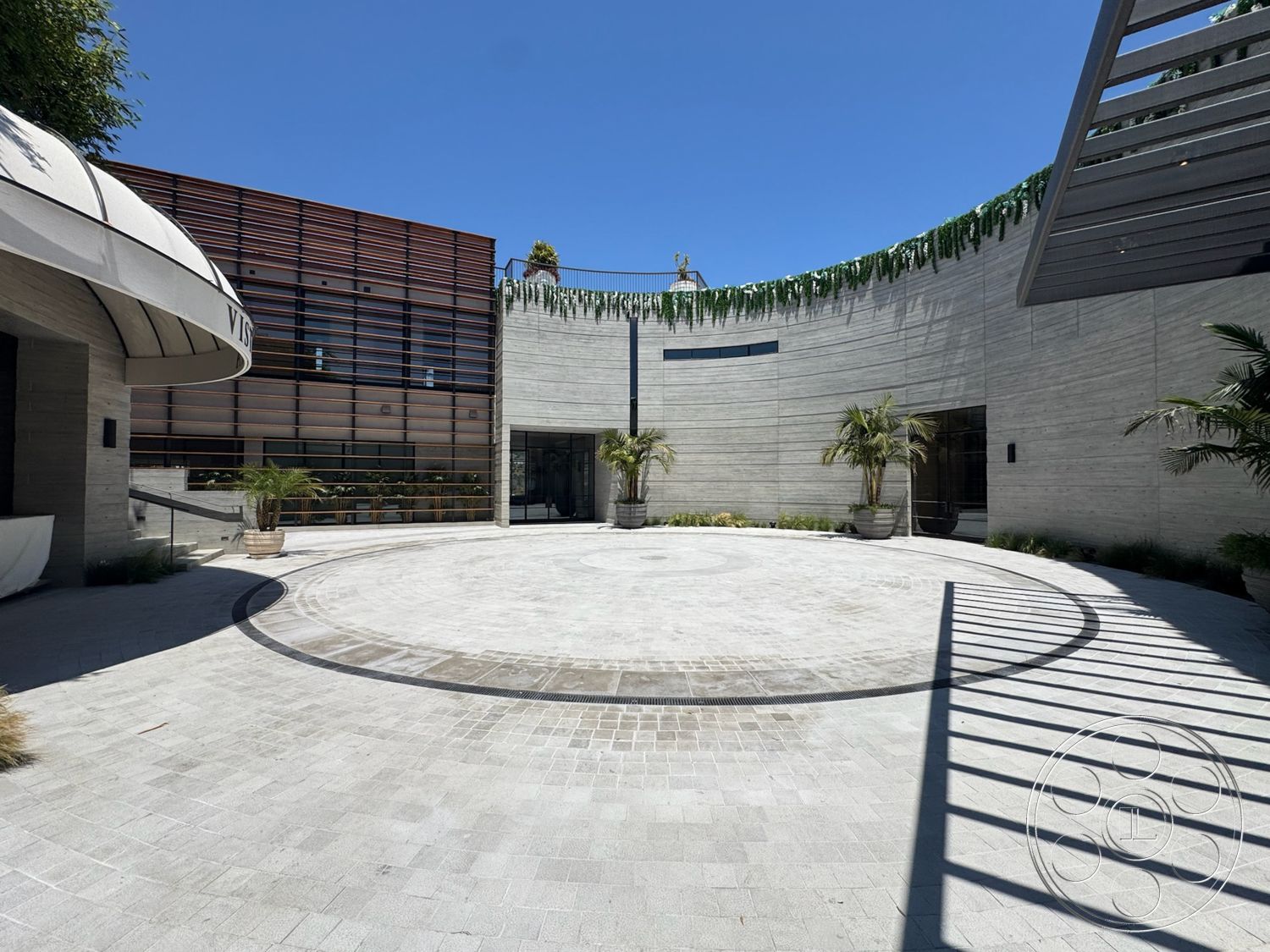 Star Villa - exterior, floor-to-ceiling windows, modern architectural style, curved concrete walls, landscaped garden planters, sunlight casting shadows, concrete courtyard flooring, wood slatted exterior facade, round focal point in courtyard
