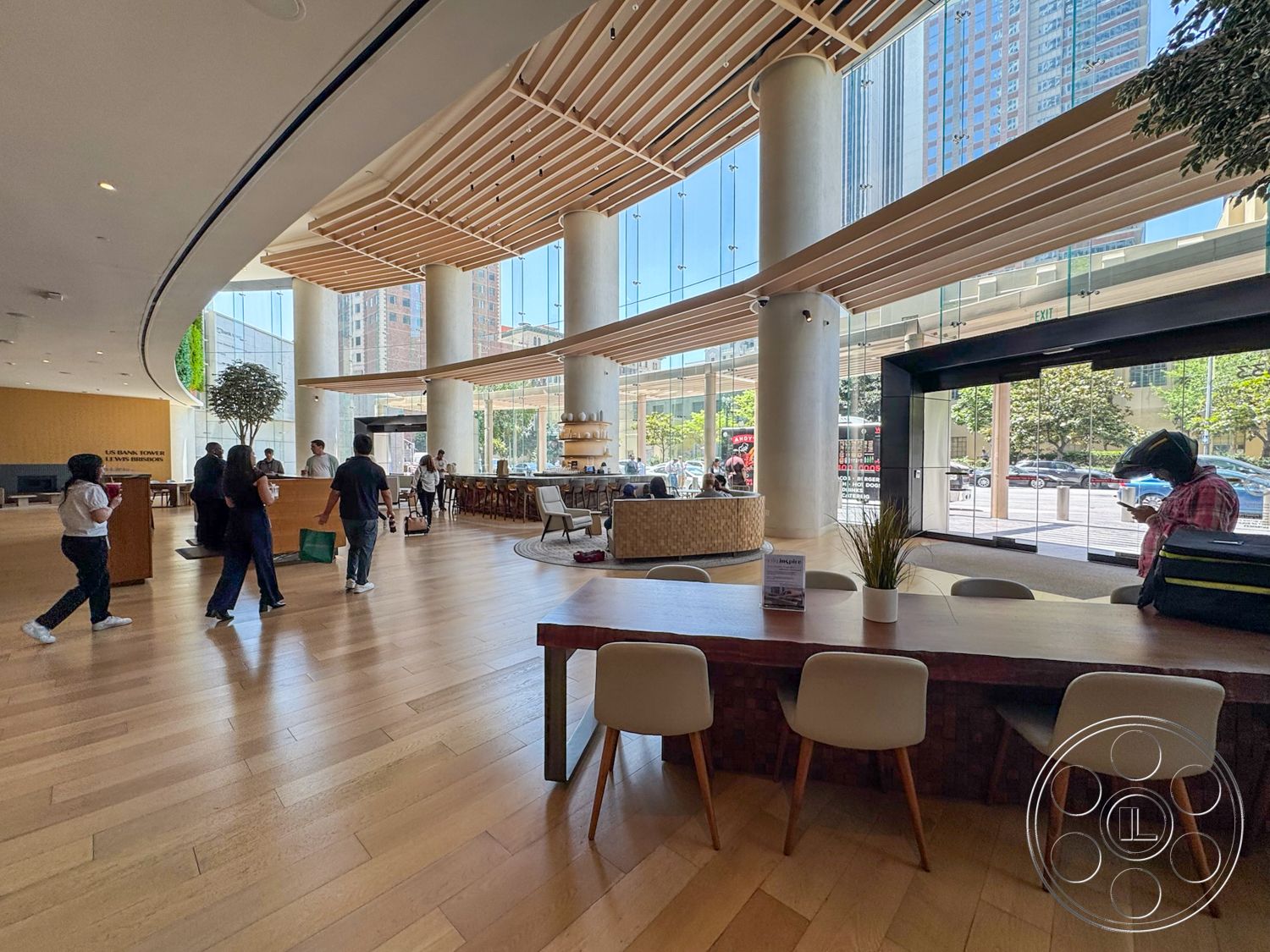 Office 123 - contemporary furniture, light hardwood flooring, natural light interior, floor-to-ceiling glass windows, rounded seating arrangement, modern reception area, exposed concrete columns, lounge seating area, urban environment setting, wooden ceiling slats, curved interior wall, interior plantscape