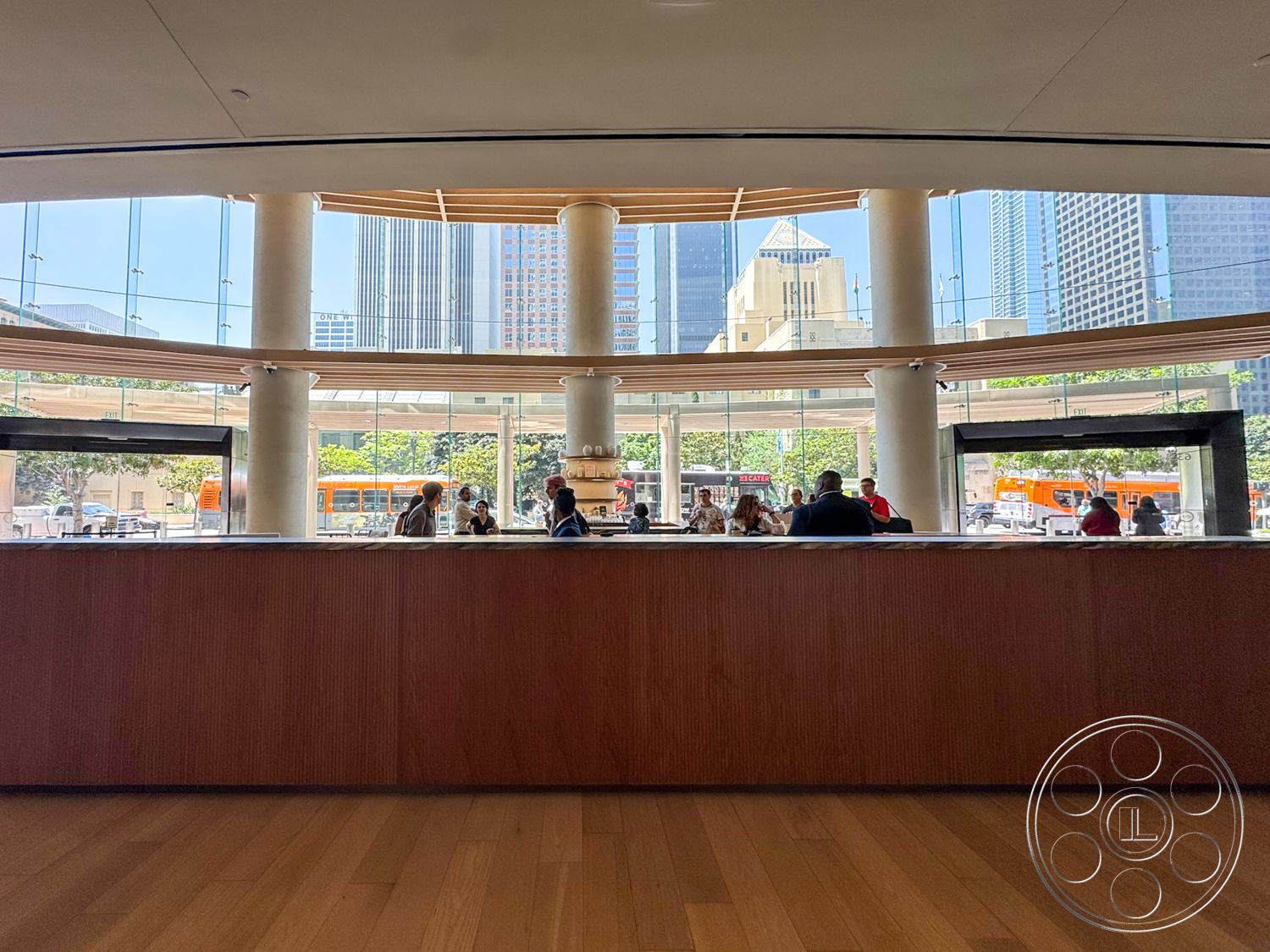Office 123 - hardwood flooring, minimalist design elements, urban setting, modern architectural style, city skyline view, open-plan layout, wooden reception desk, natural light flooding, exposed concrete columns, horizontal wood ceiling slats, glass wall facade
