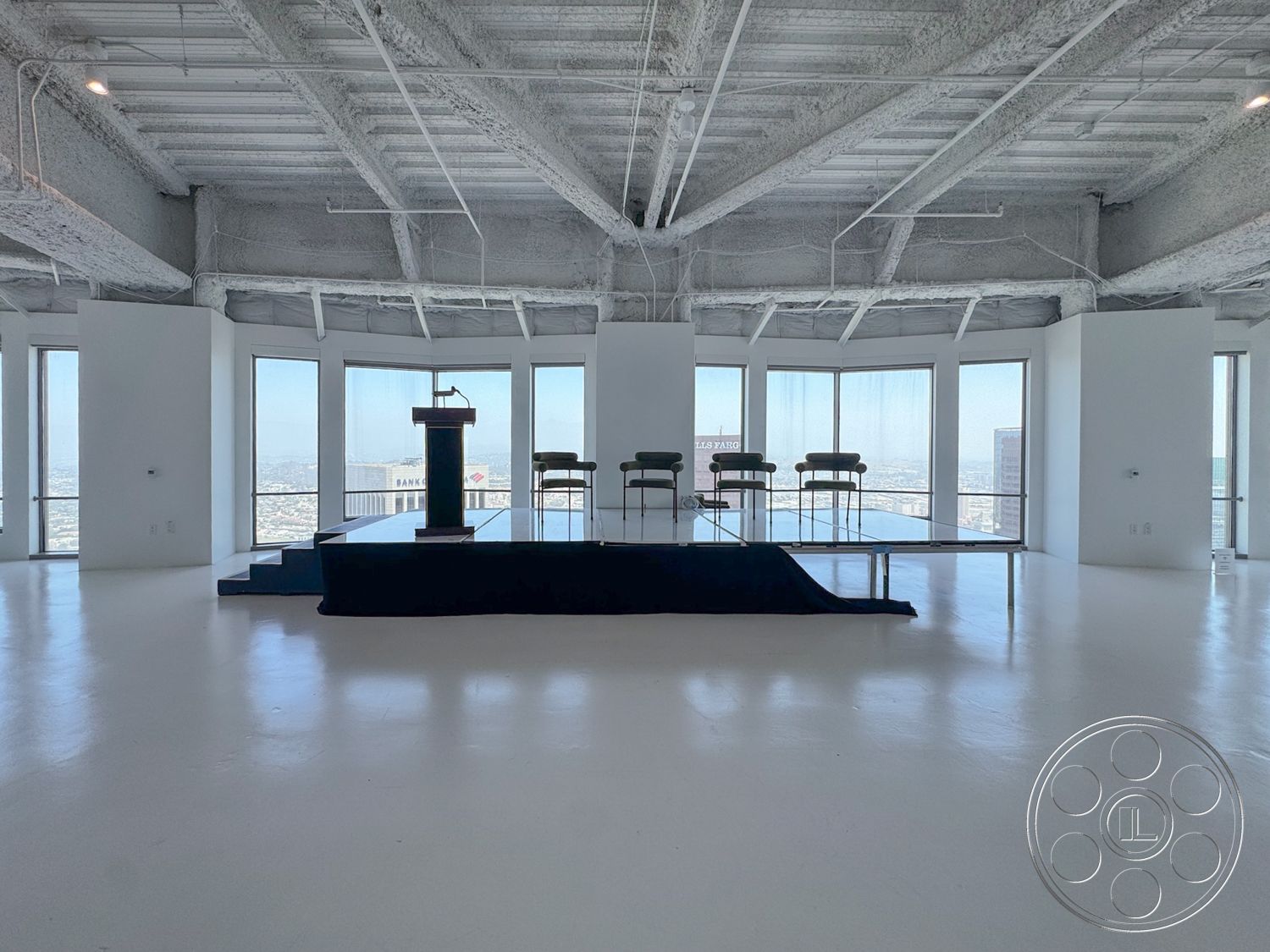 Office 123 - polished concrete flooring, minimalist furniture, floor-to-ceiling windows, urban skyline view, white painted walls, curved window design, exposed metal truss ceiling, modern podium, rectangular stage area