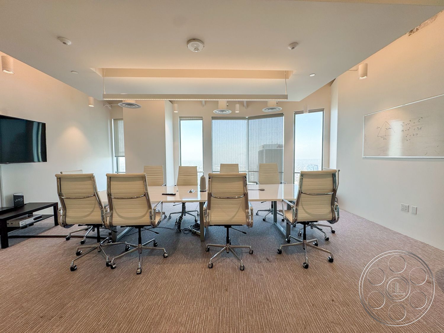Office 123 - textured carpet flooring, white painted walls, modern office design, glass conference room windows, metal conference table, upholstered ergonomic office chairs, central recessed lighting, wall-mounted flat-screen television, whiteboard wall panel