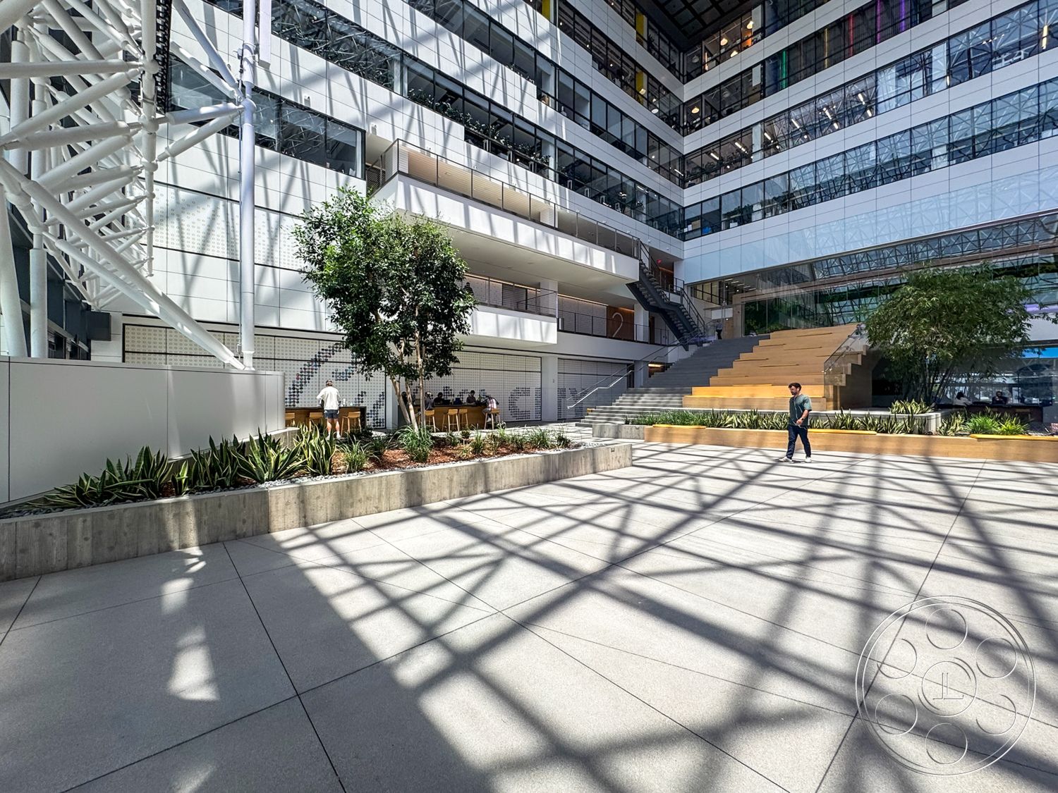 The Atrium - exterior, modern design elements, vertical greenery, landscaped garden beds, open atrium space, glass curtain wall, steel structural elements, wooden seating area, industrial architectural style, natural sunlight exposure, staircase with metal railings, concrete plaza flooring, concrete planter walls