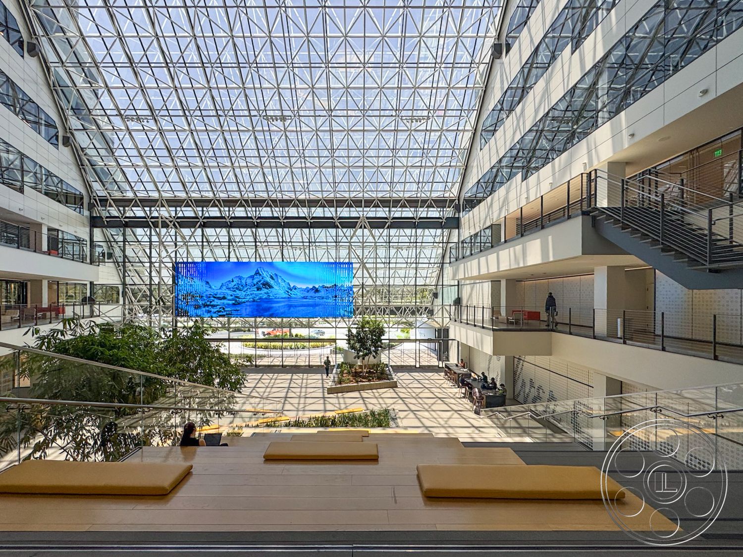 The Atrium - modern design elements, concrete walls, indoor greenery, steel frame structure, floating staircase, open-plan layout, urban office space, natural light environment, glass atrium roof, hardwood floor seating area, digital display wall, reinforced glass windows, multi-story atrium, railings with steel details