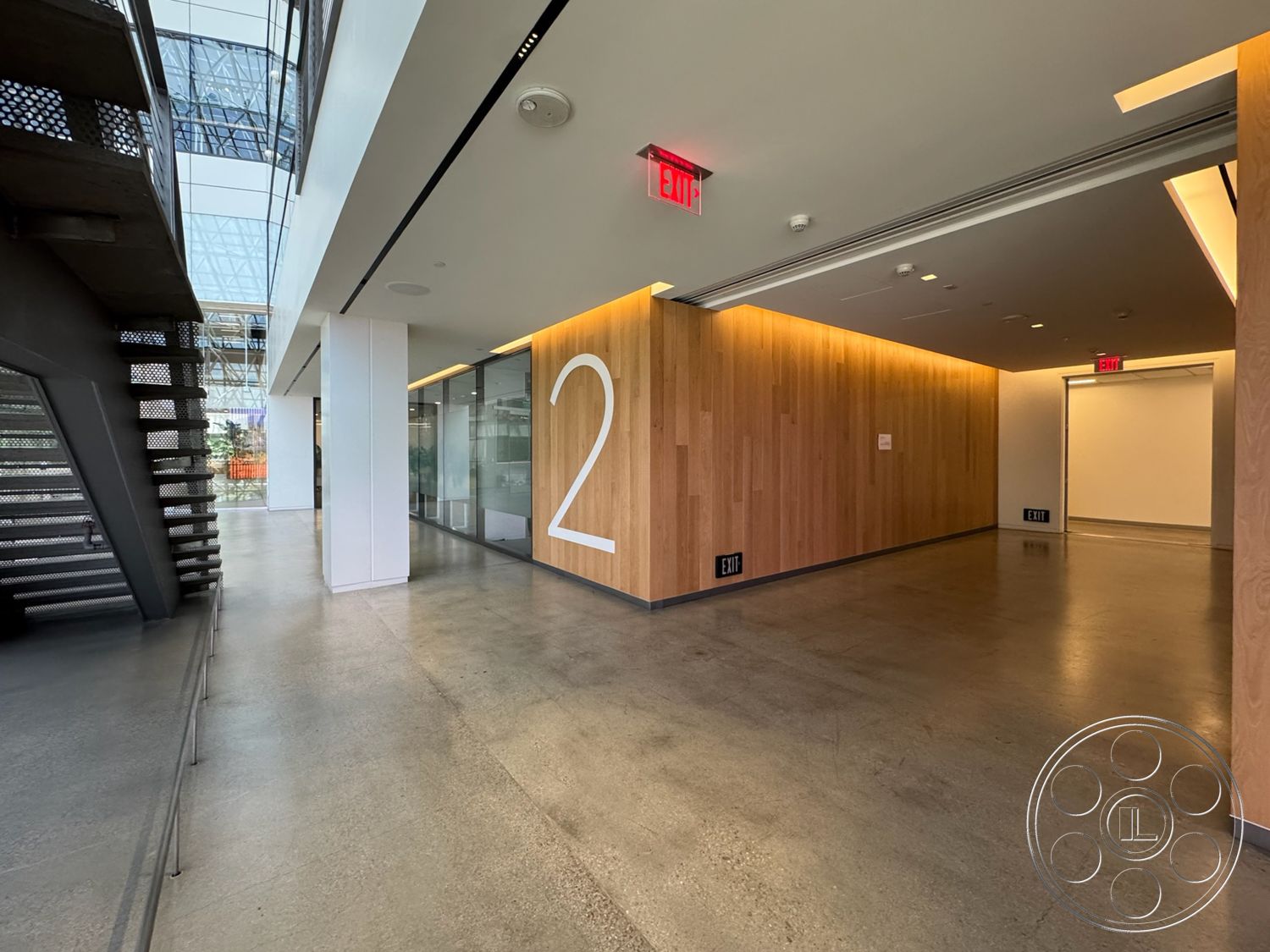 The Atrium - open space layout, ambient lighting, floor-to-ceiling windows, modern architectural style, exposed concrete floor, interior hallway, wood wall paneling, steel stair railing, numbered wall feature