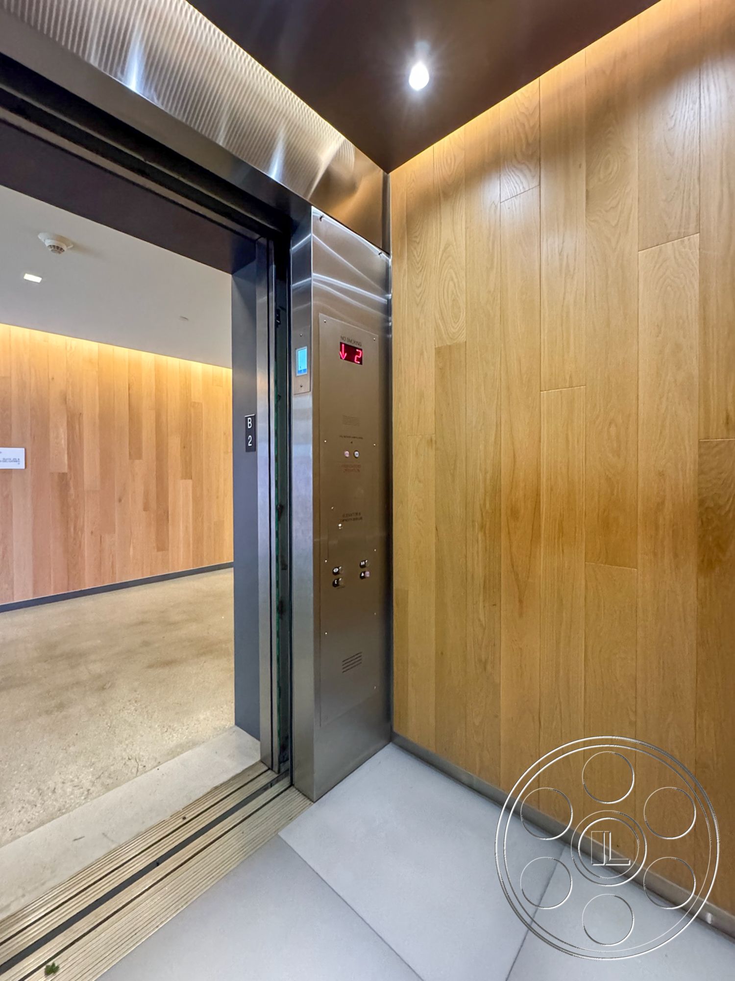 The Atrium - polished concrete flooring, modern lighting fixtures, minimalist architectural style, stainless steel elevator doors, wood panel accent wall, elevator control panel, interior elevator, square corner design