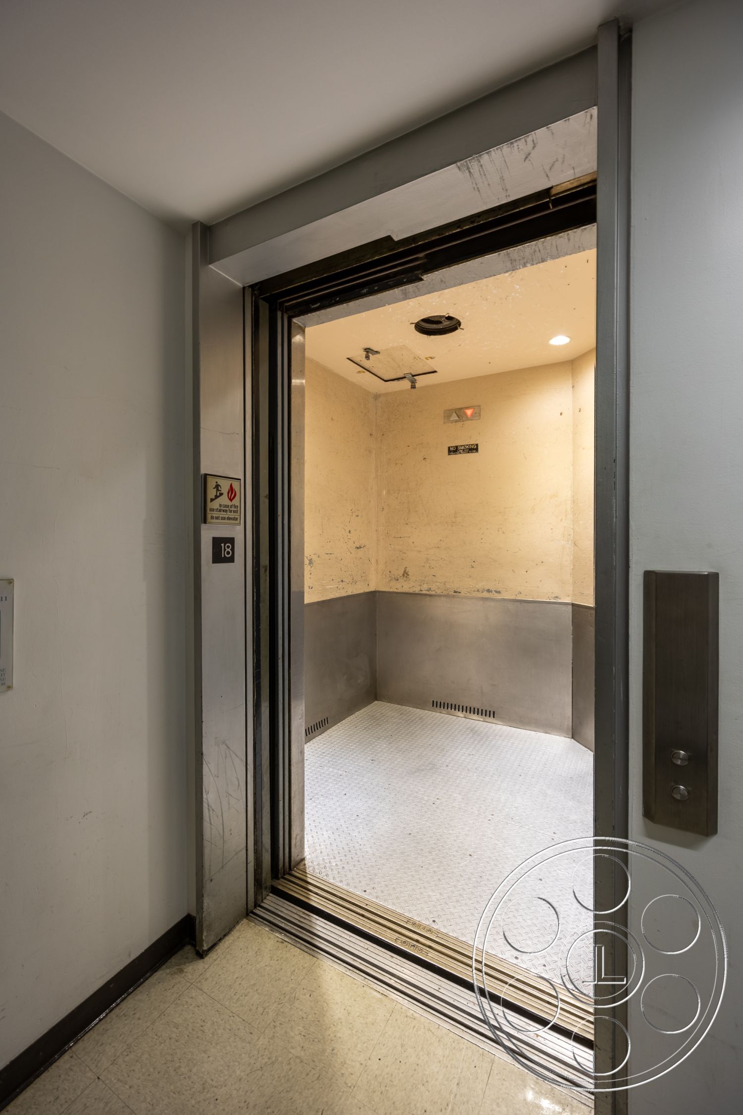 Rooftop 53 - fluorescent ceiling lights, interior elevator, metal elevator walls, metal floor plate, rubber baseboard, hinged elevator doors, plastic elevator control panel, industrial style elevator