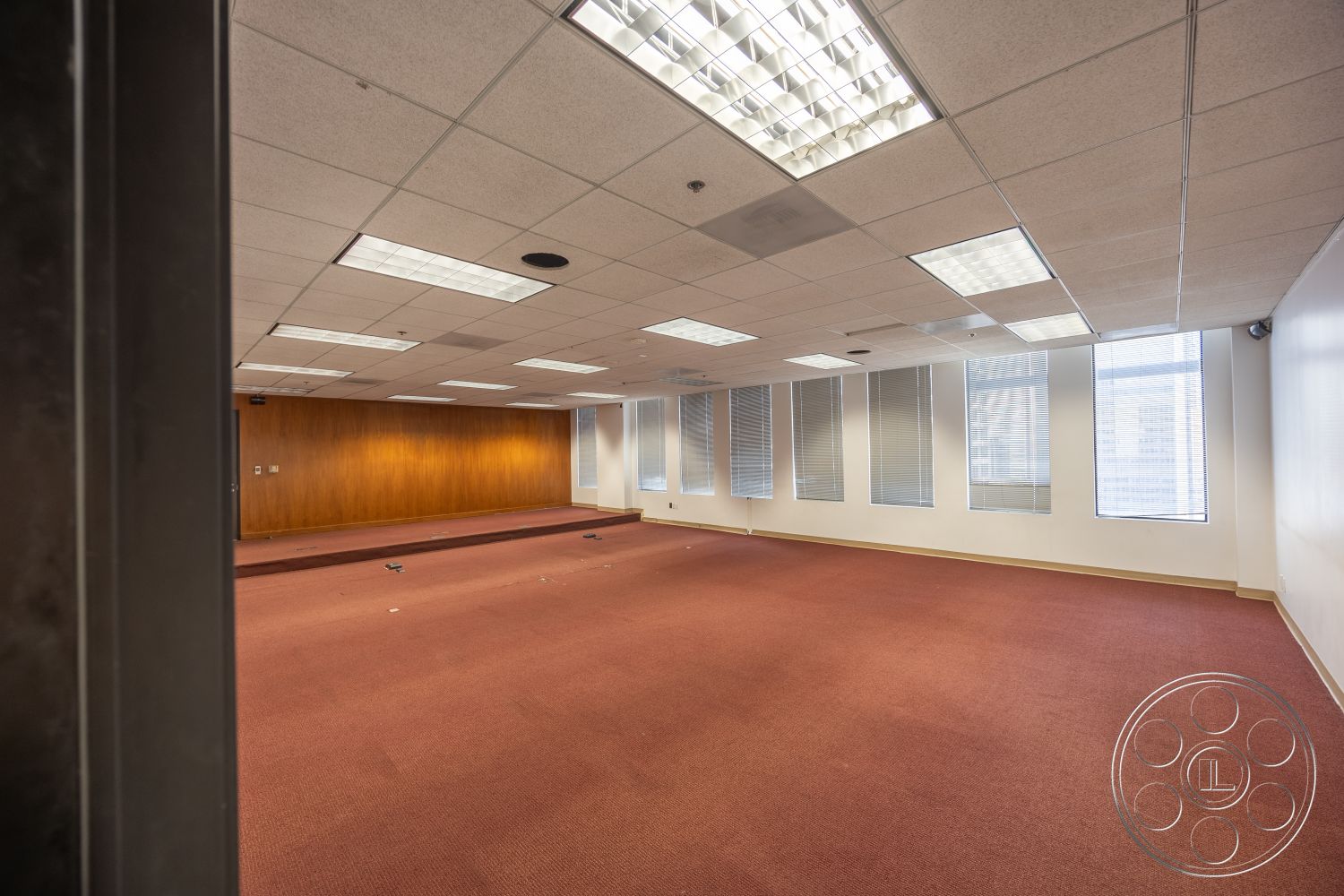 Rooftop 53 - open floor plan, floor-to-ceiling windows, carpet flooring, acoustic ceiling tiles, recessed lighting fixtures, modern office space, wood panel accent wall, blinds window treatment, raised platform area