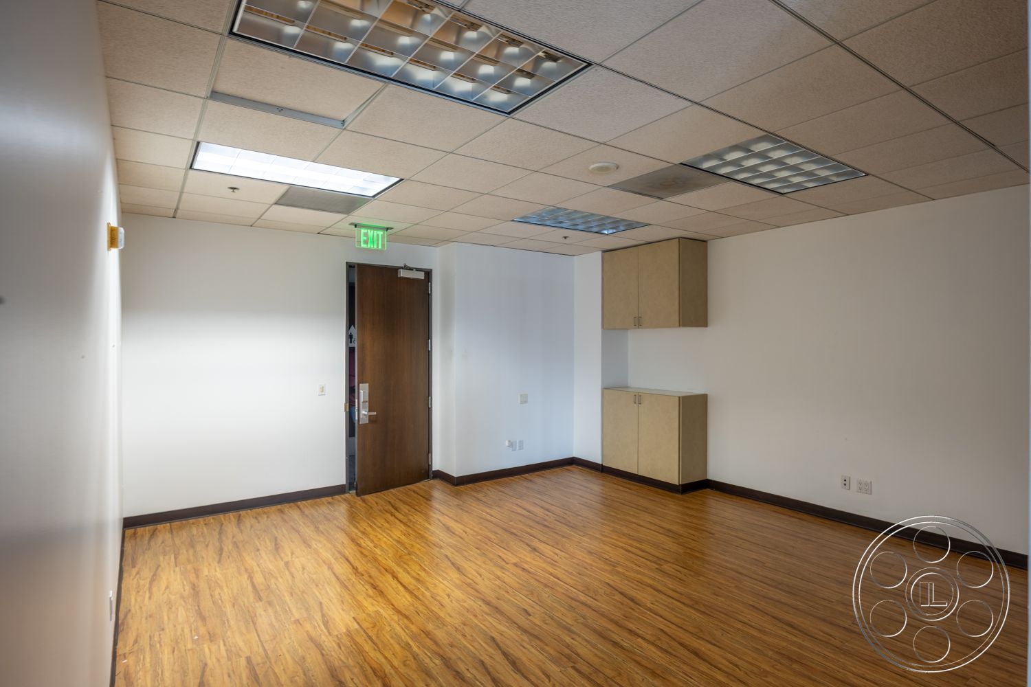 Rooftop 53 - light wood cabinetry, brown wooden door, laminate wood flooring, white painted walls, modern office design, drop ceiling tiles, flush mount ceiling lights, empty office space