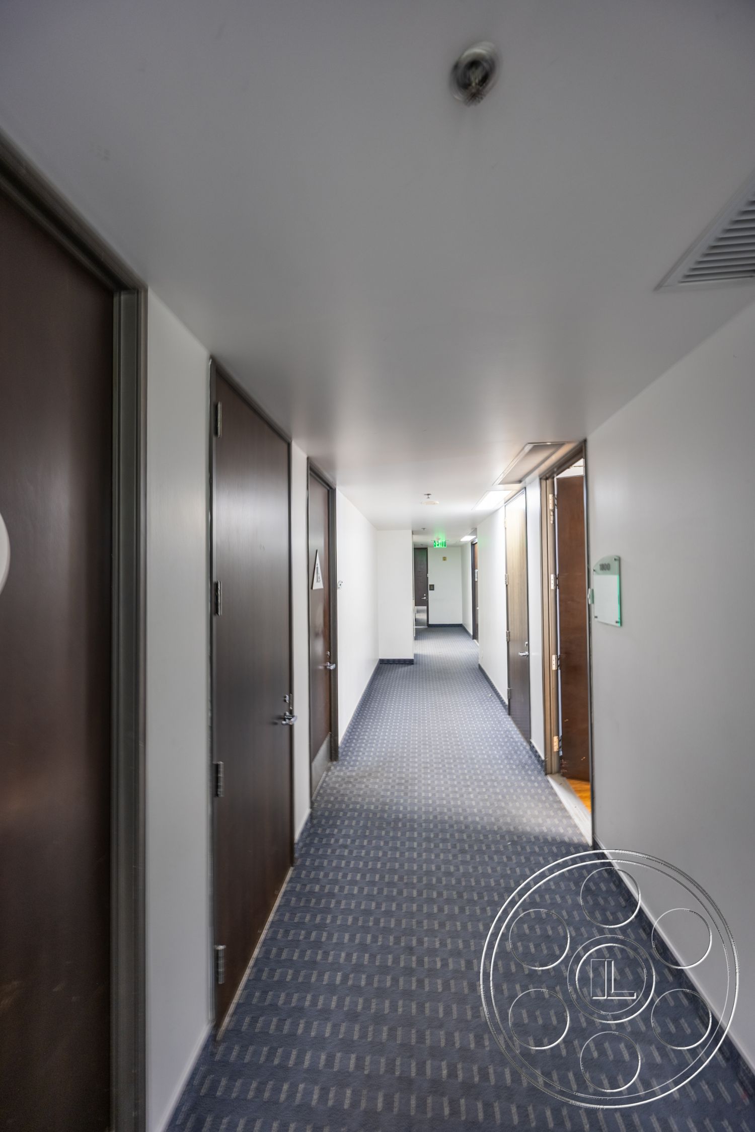 Rooftop 53 - modern architectural style, recessed ceiling lights, interior hallway, white painted walls, metal door handles, carpet hallway flooring, striped carpet design, wood doors
