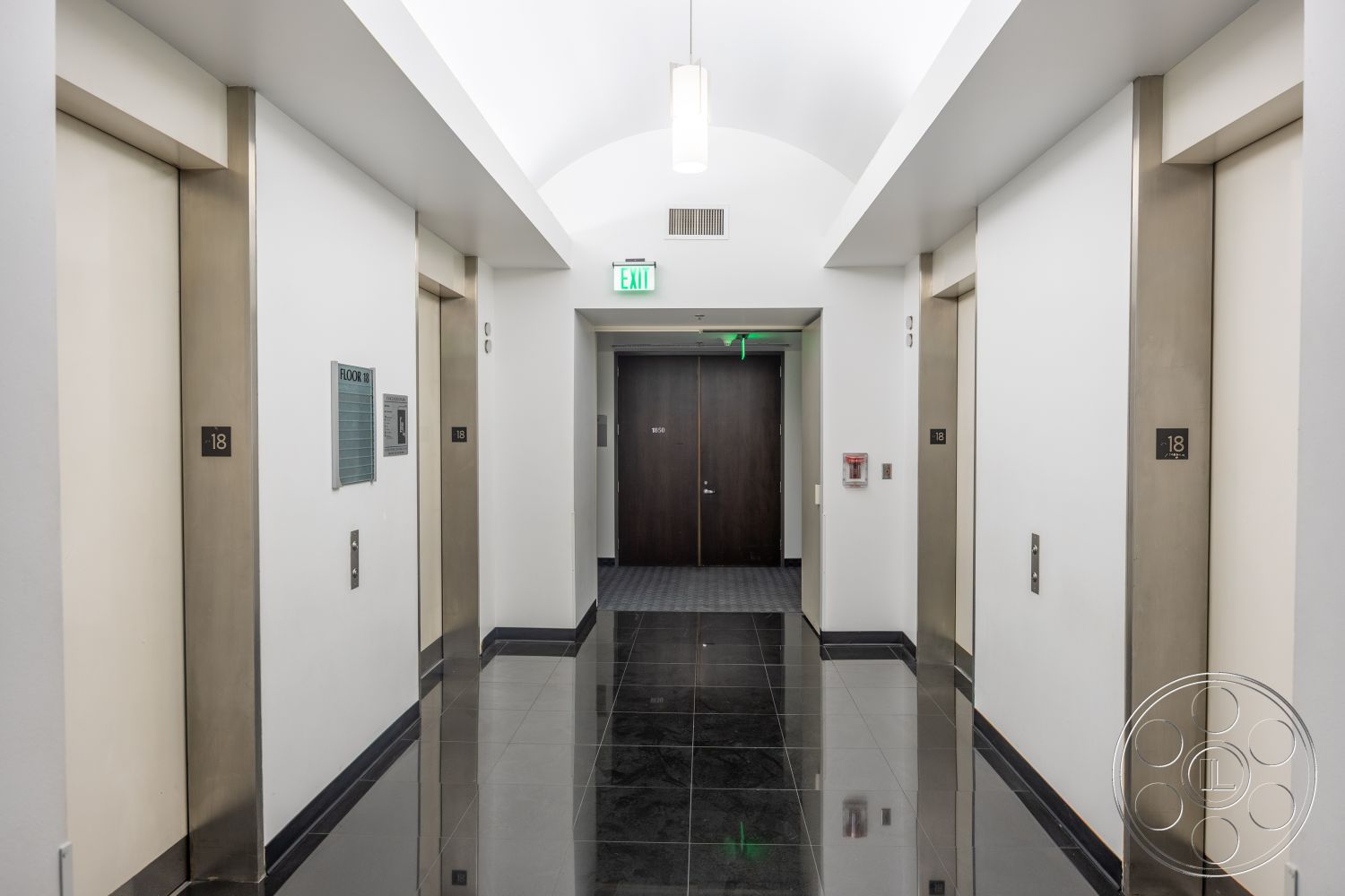 Rooftop 53 - arched ceiling, white painted walls, recessed LED lighting, stainless steel elevator doors, modern corridor design, dark wood entrance door, polished black tile flooring, brushed metal wall signage