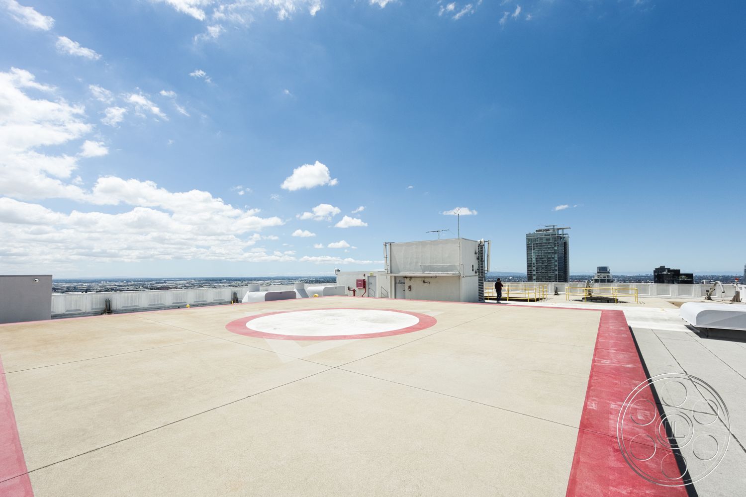 Rooftop 53 - exterior, urban skyline view, cloudy sky, concrete helipad surface, flat rooftop setting, red painted helipad markings