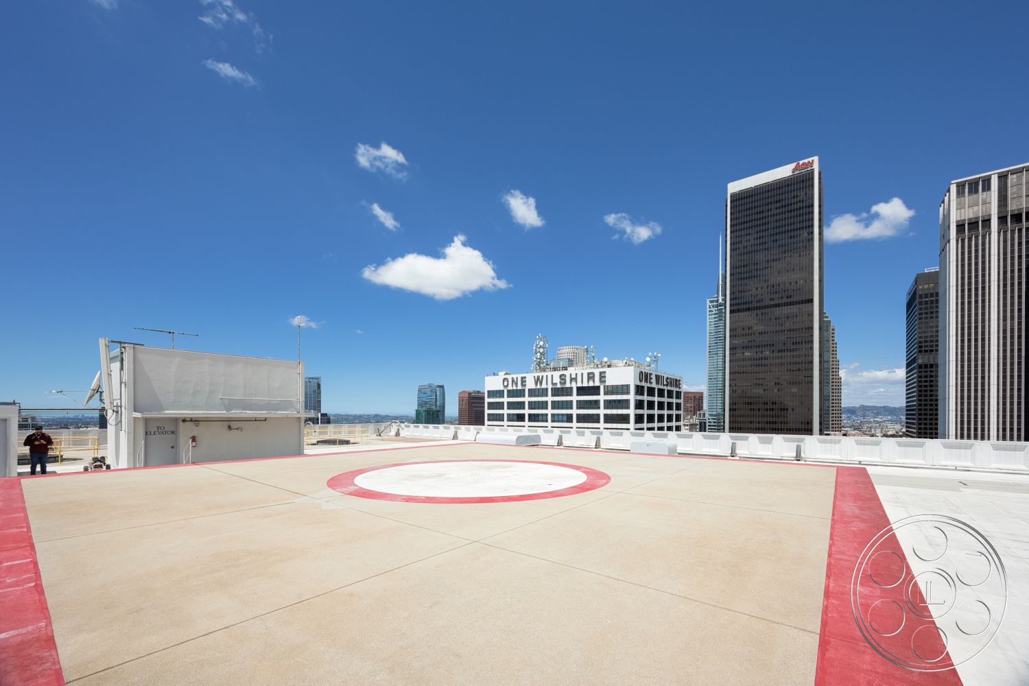 Rooftop 53 - exterior, urban skyline view, flat rooftop structure, commercial building environment, concrete rooftop, modern high-rise buildings, red painted helipad circle