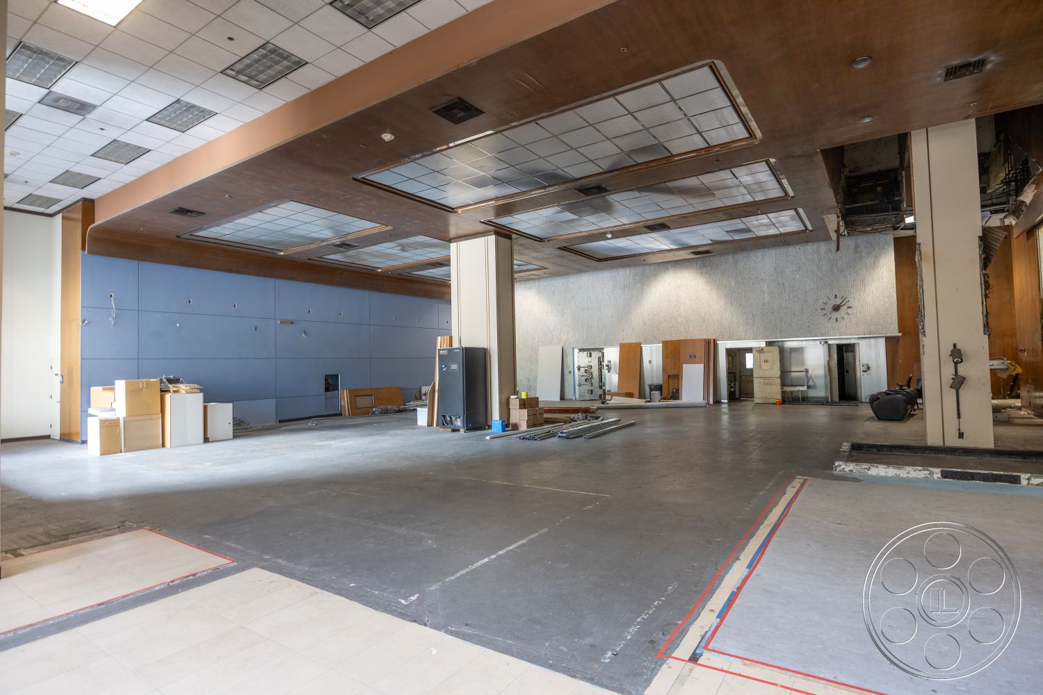 Rooftop 53 - concrete floor, commercial space, square ceiling tiles, exposed ceiling grid, large open layout, wood paneling accent wall, unpainted drywall, blue drywall walls, utility installation areas