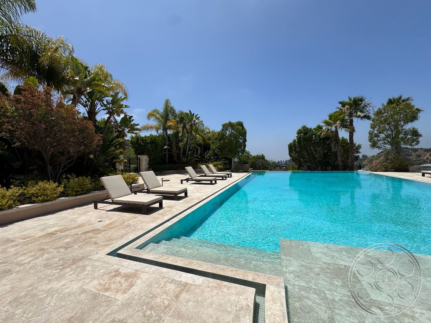 Beverly Compound - exterior, palm trees, mountain view, green shrubbery, clear blue sky, tropical landscaping, sun loungers, infinity edge, rectangular pool, stone patio flooring, concrete pool border, natural stone pool deck