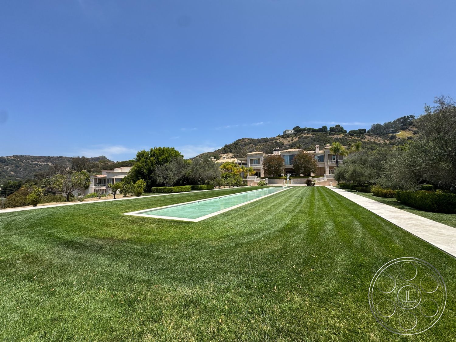 Beverly Compound - exterior, modern architecture, concrete patio, mature trees, grass lawn, mountain backdrop, rectangular pool, landscaped garden areas, pool water surface, walkway edging