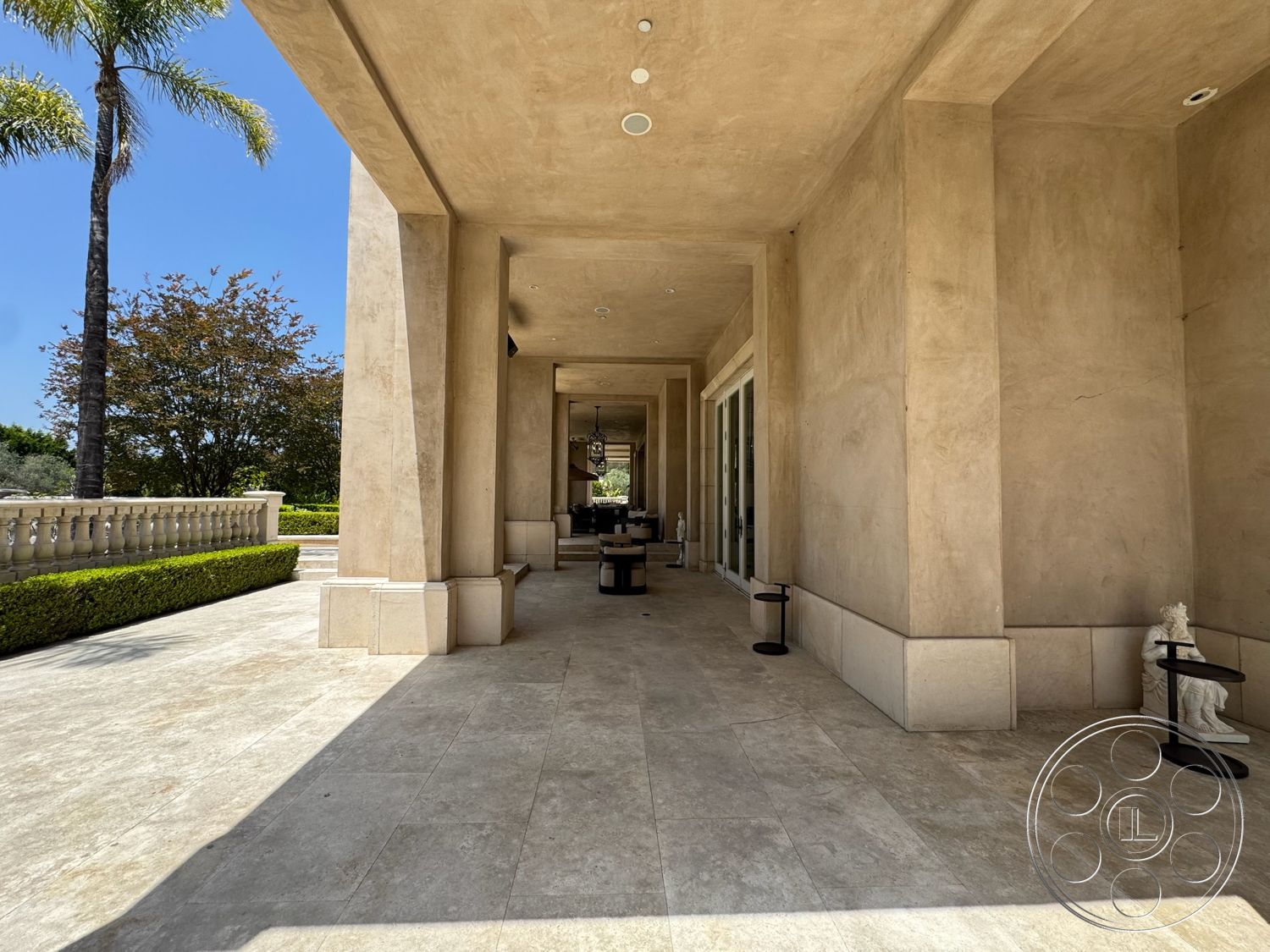 Beverly Compound - coffered ceiling, exterior, palm trees, natural lighting, arched doorways, textured plaster walls, open-air terrace, modern outdoor seating, luxurious entrance, landscaped garden area, travertine patio flooring