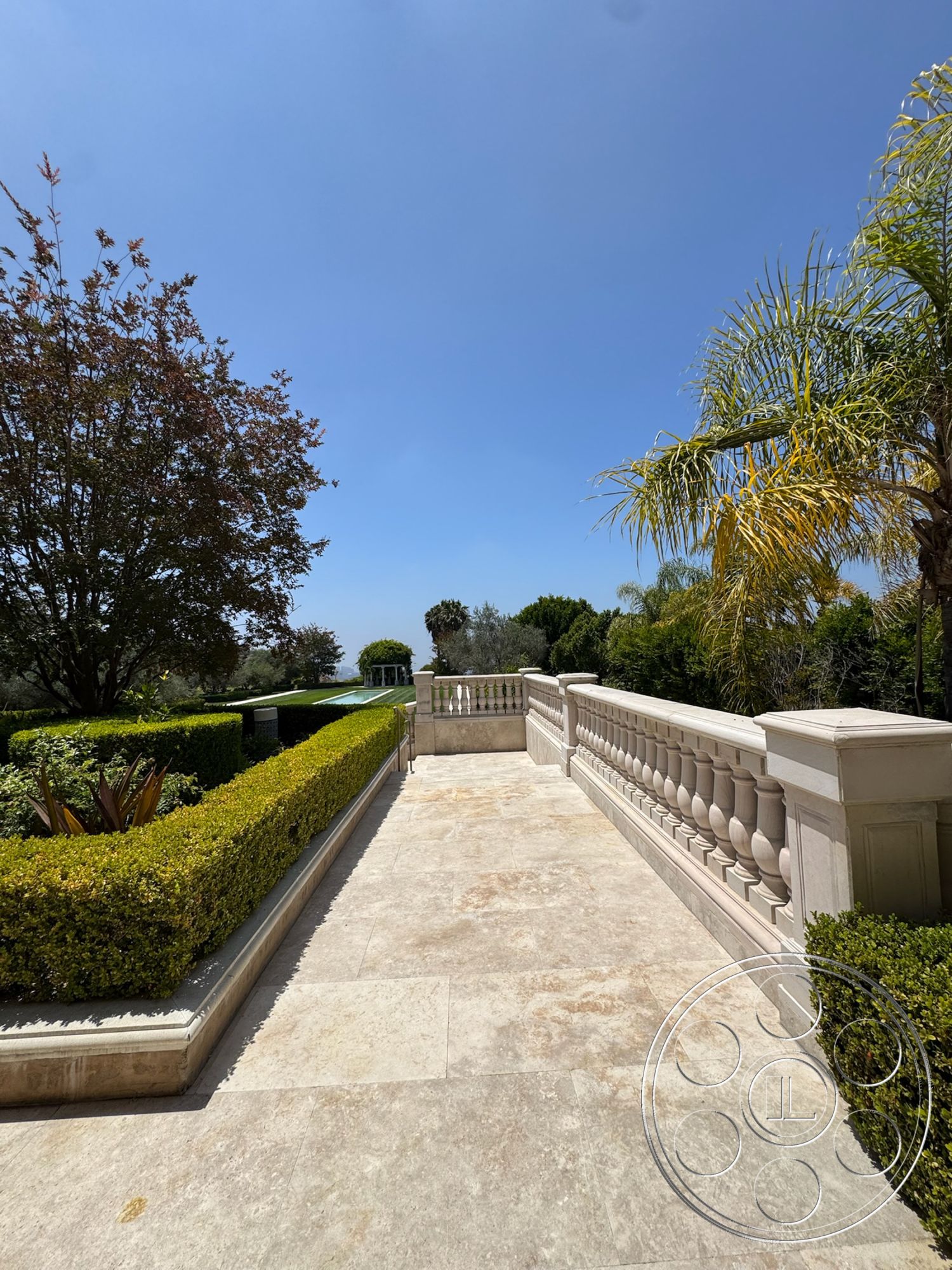 Beverly Compound - exterior, palm trees, outdoor setting, manicured hedges, landscaped garden area, flagstone patio flooring, decorative shrubbery, sunny sky, stone balustrade railing, view of swimming pool