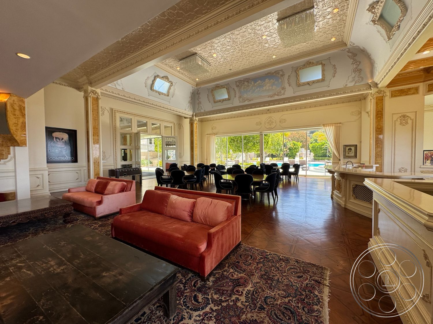 Beverly Compound - decorative area rug, open floor plan, decorative crown molding, large floor-to-ceiling windows, ornate wall detailing, dark wood coffee table, vaulted living room ceiling, intricate plaster ceiling moldings, soft pink velvet sofas, wood panel flooring, modern dining area with round black chairs