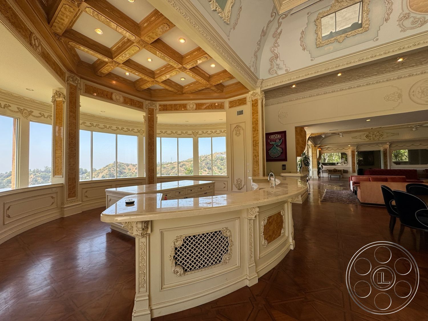 Beverly Compound - modern decor, bright natural light, floor-to-ceiling windows, intricate moldings, scenic hillside view, marble kitchen countertops, rectangular kitchen island, parquet wood flooring, open floor layout, coffered wood ceiling, wood paneling details, luxurious living area, ornately decorated walls