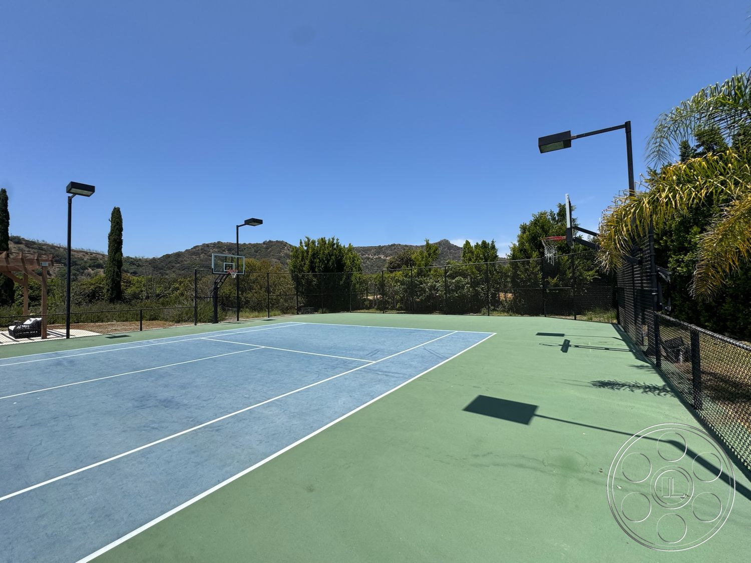 Beverly Compound - landscaped garden, surrounding greenery, mountain view, basketball hoop, green court surface, outdoor lighting fixtures, sunny outdoor setting, exterior tennis court, blue court lines, hardcourt surface tennis court, fencing around court