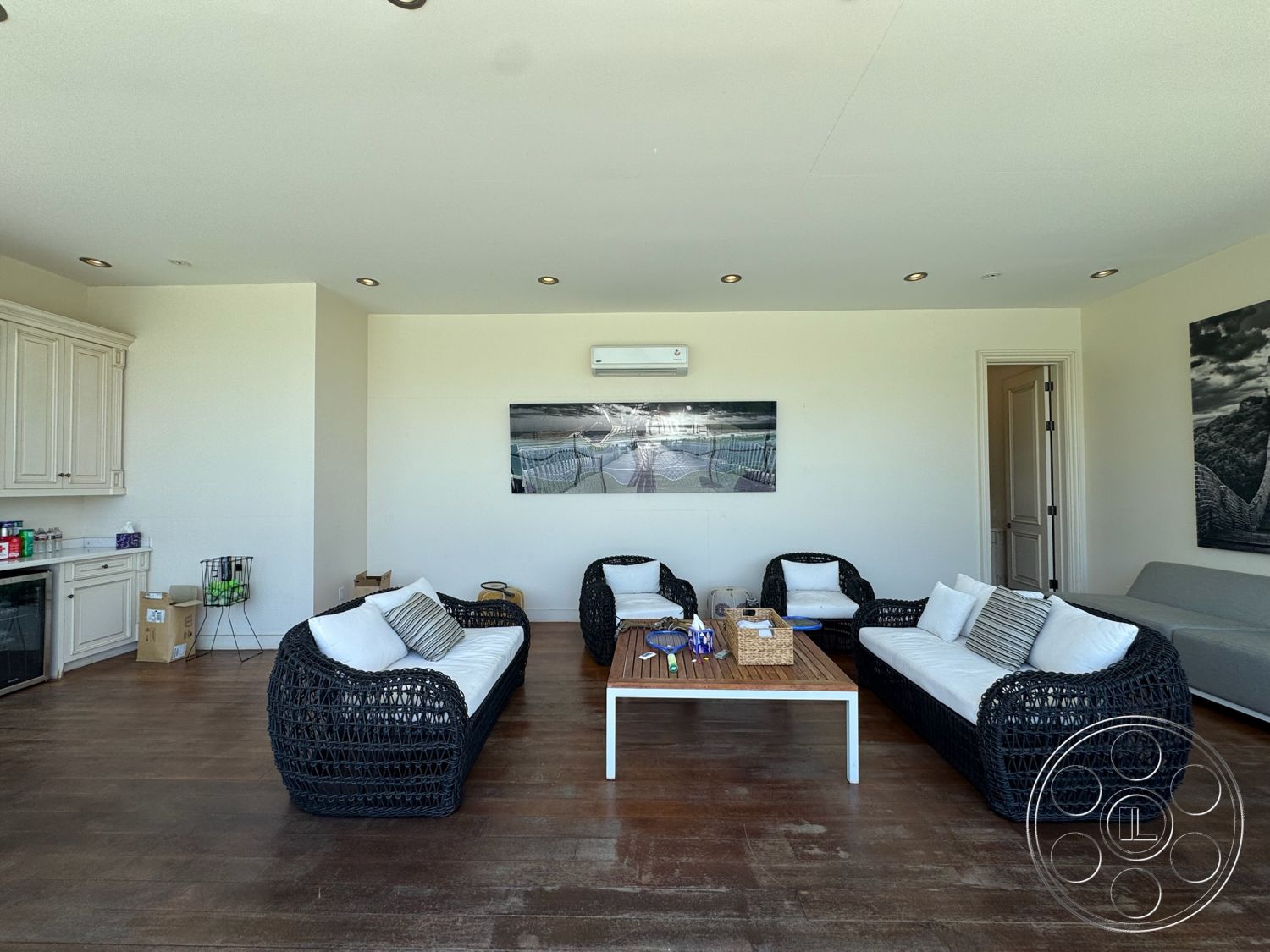 Beverly Compound - light-colored walls, open floor plan, modern coffee table, floor-to-ceiling windows, relaxed seating area, exposed ceiling, hardwood living room floors, ambient recessed lighting, wicker seating with cushions, kitchenette with cabinetry, subtle art decor