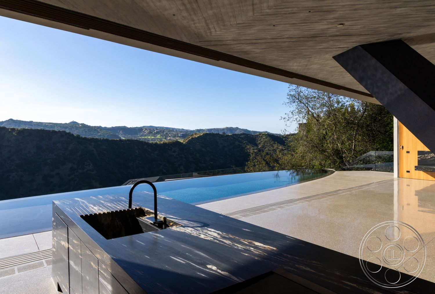 Modern 516 - concrete flooring, minimalist design elements, sliding glass doors, glass railings, floor-to-ceiling windows, modern architectural style, infinity pool, natural stone countertop, mountain view setting, cantilevered roof structure, steel outdoor kitchen island