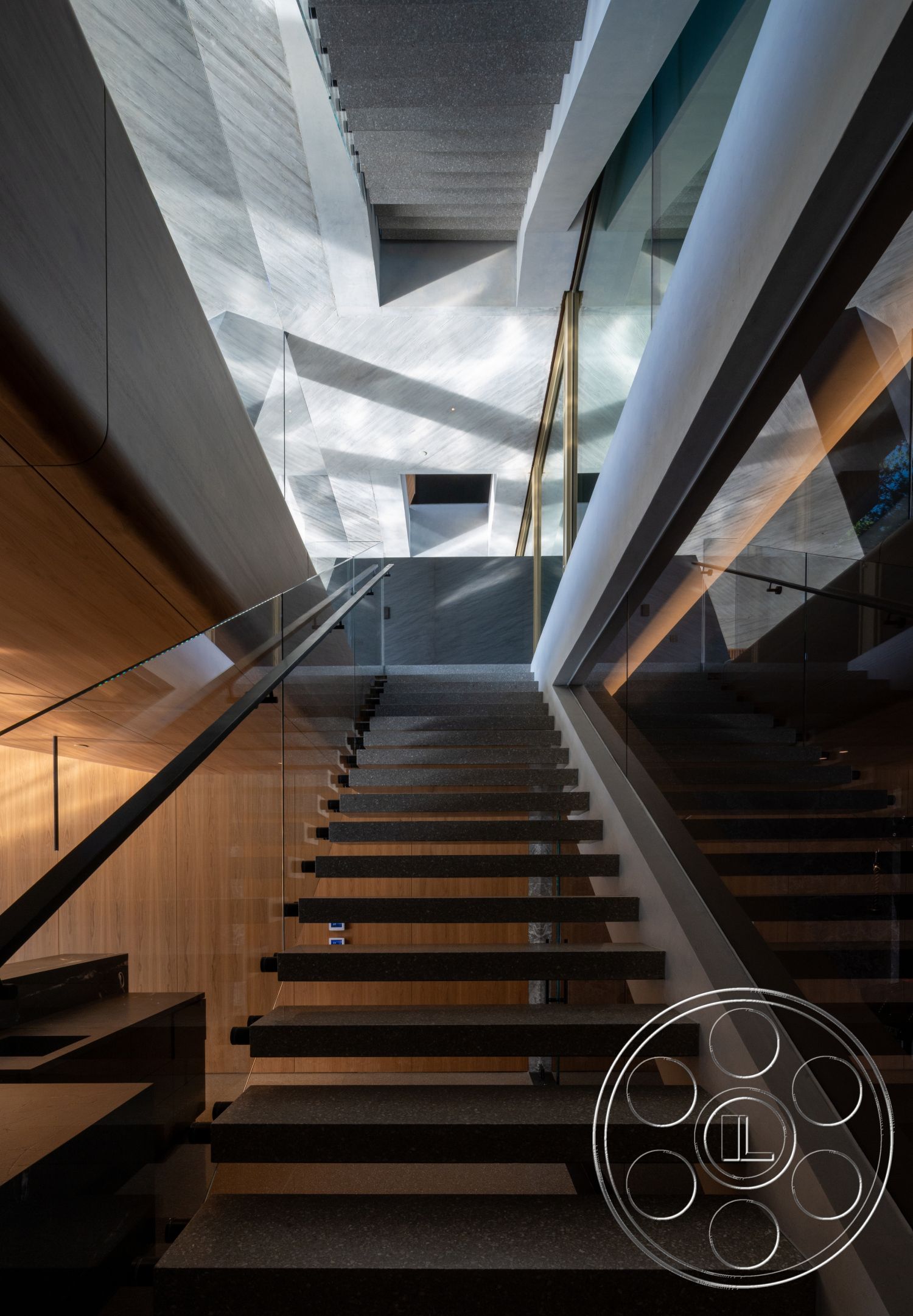 Modern 516 - minimalist interior style, modern architectural design, linear lighting fixtures, open stairwell, natural wood wall paneling, geometric ceiling details, floating staircase with textured stone steps, glass balustrades, high ceilings with angular lines